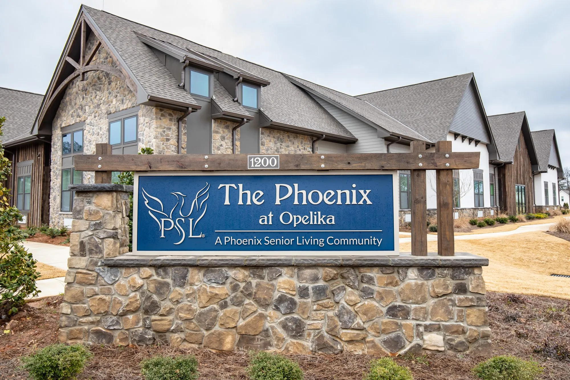 Senior living community monument sign in stone and timber with the phoenix logo, interior design by Banko Design at The Phoenix at Opelika, Opelika, Alabama