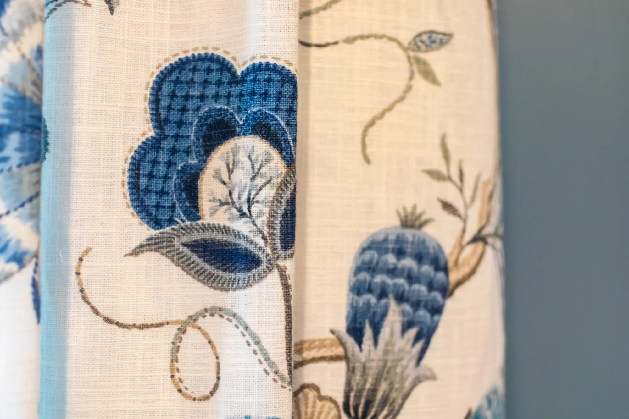 Senior living interior detail: cream drapery with blue embroidered flowers and pomegranates