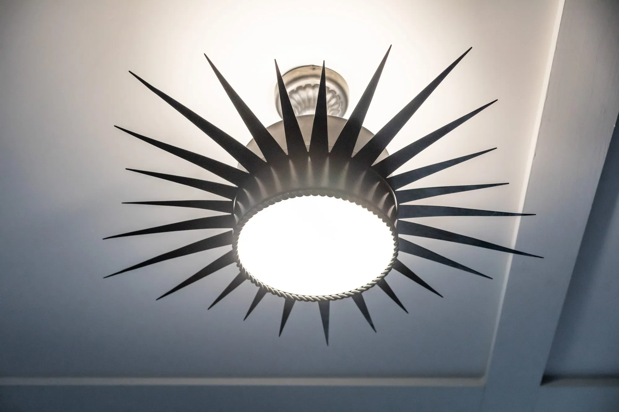 Senior living interior detail: black starburst ceiling light with a frosted glass dome on a white tray ceiling