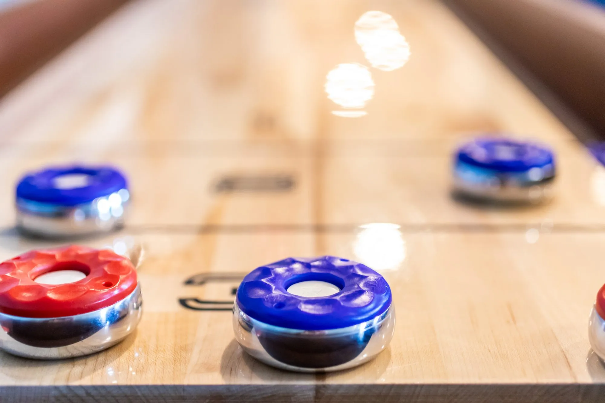 Senior living interior detail: red and blue shuffleboard pucks on a polished wood table