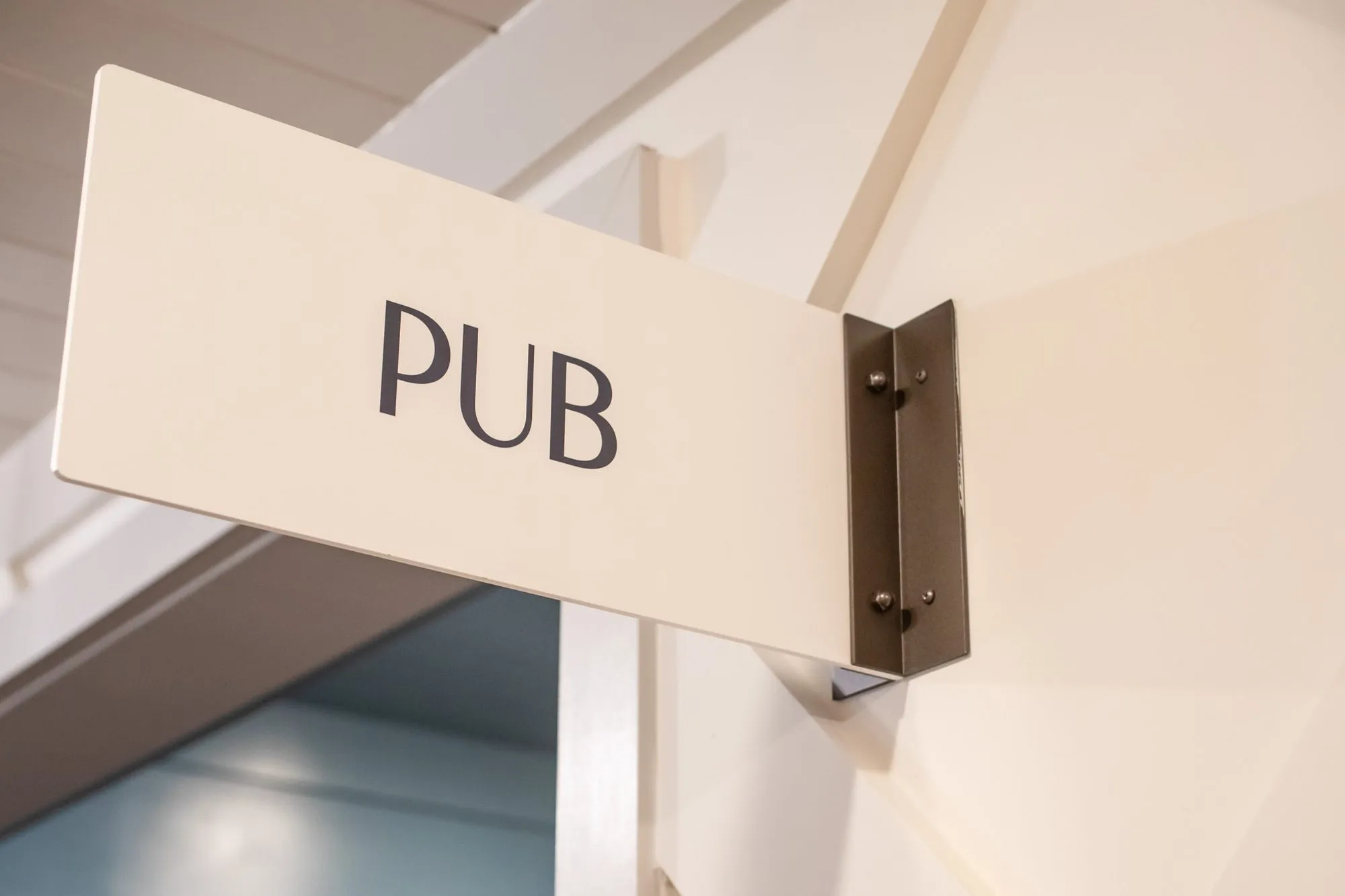 Senior living interior detail: Pub sign projecting from a white wall, seen at an angle