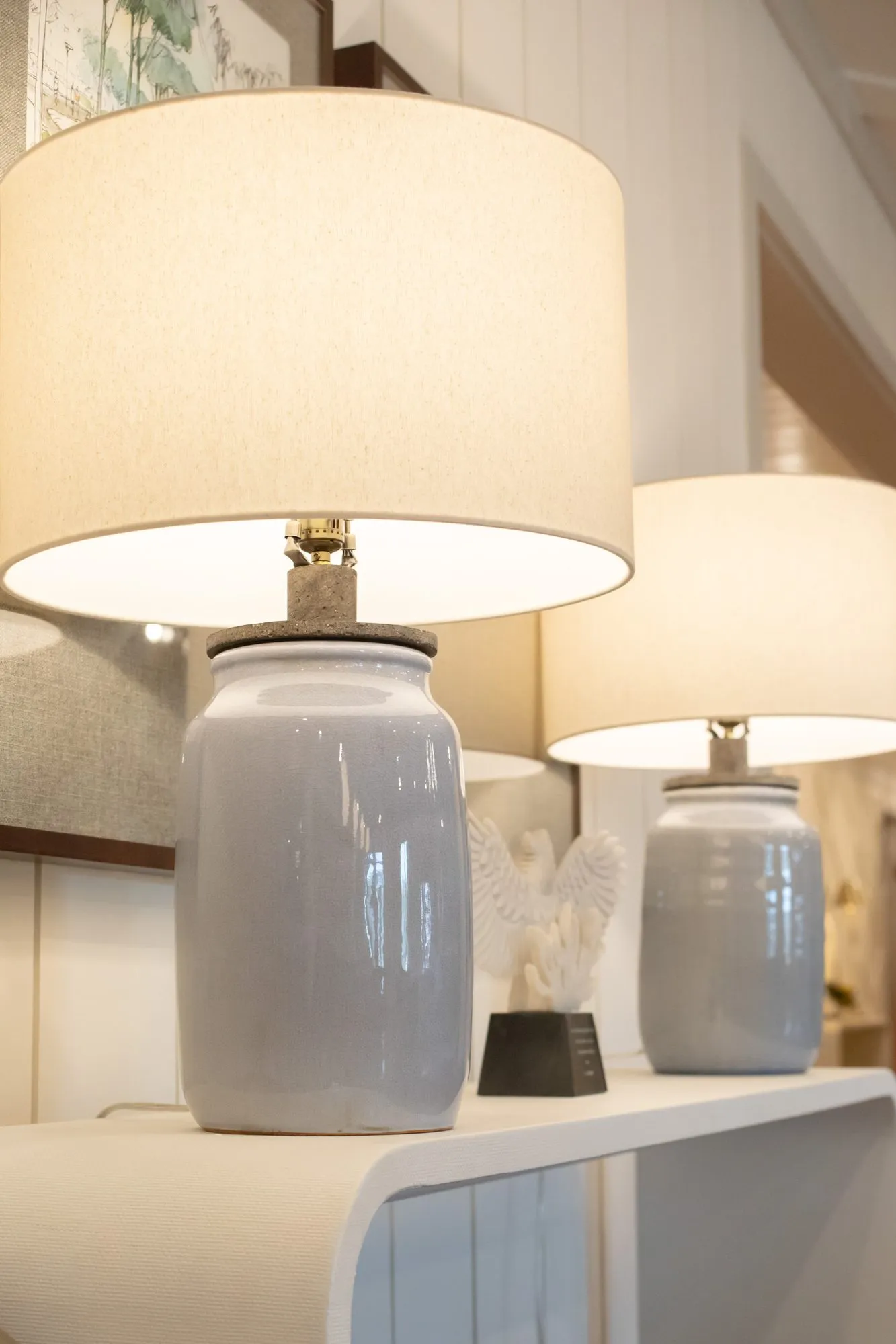 Senior living interior detail: pair of grey ceramic table lamps with drum shades on a white console