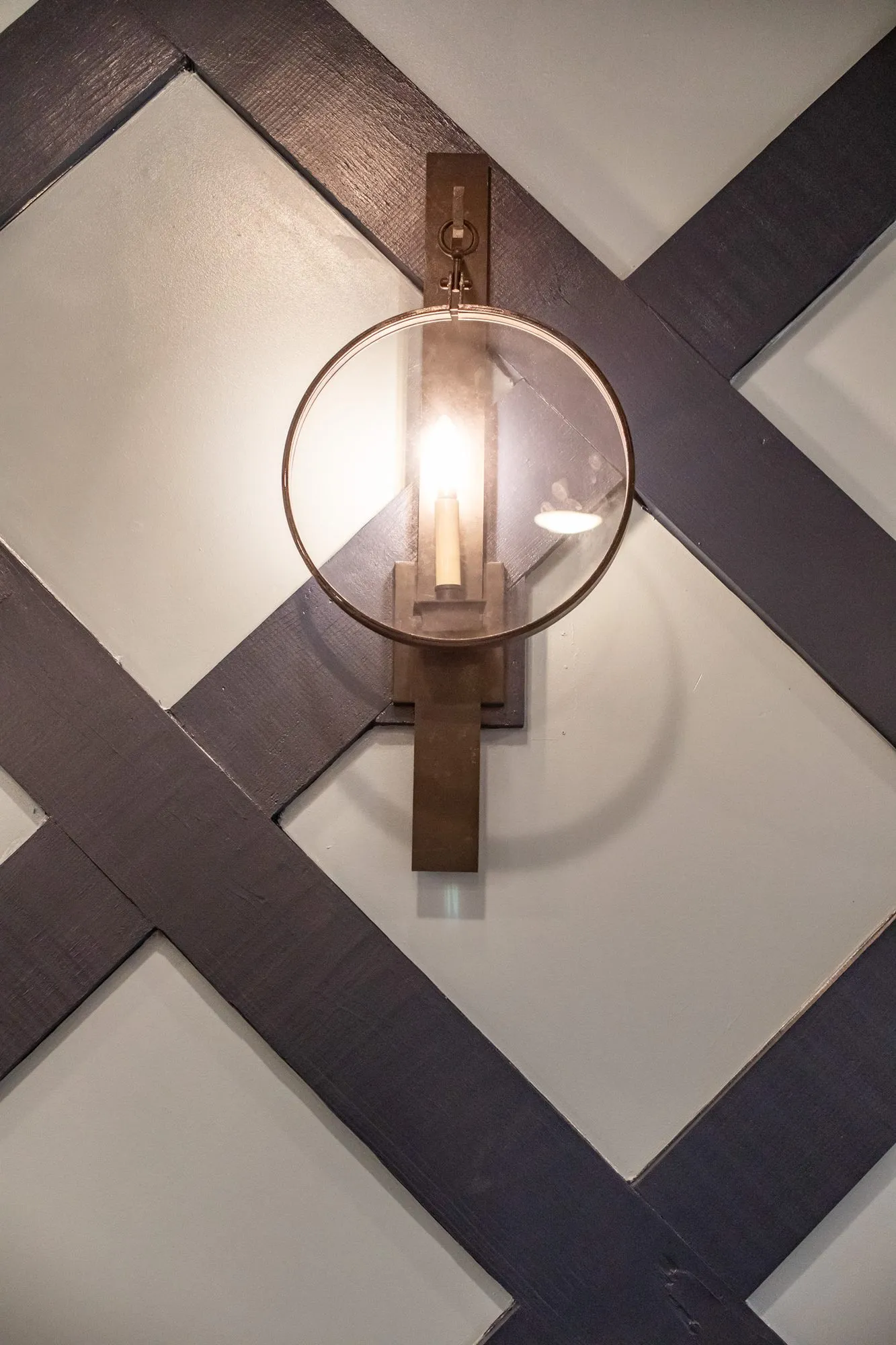 Senior living interior detail: glass globe wall sconce on navy lattice millwork over pale blue