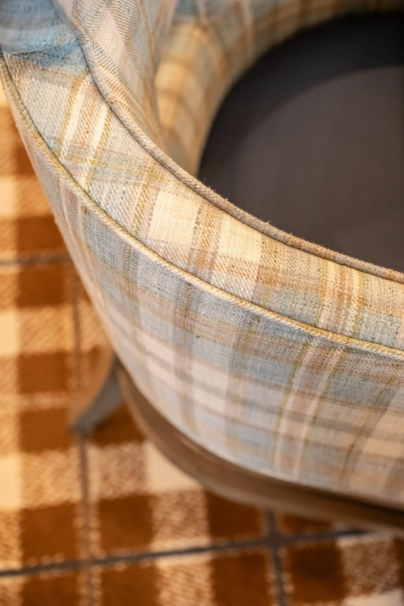 Senior living interior detail: plaid upholstered barrel chair back over an orange plaid carpet