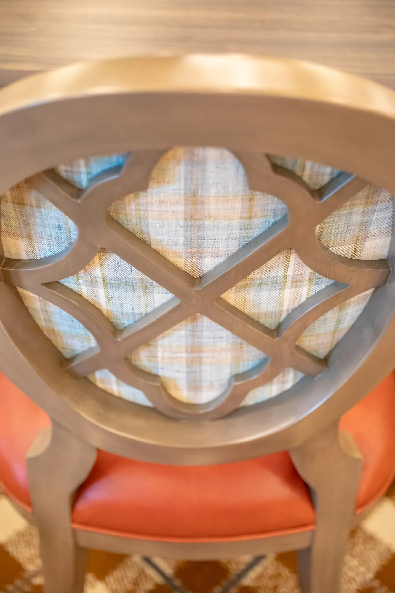 Senior living interior detail: quatrefoil lattice chair back with a coral seat