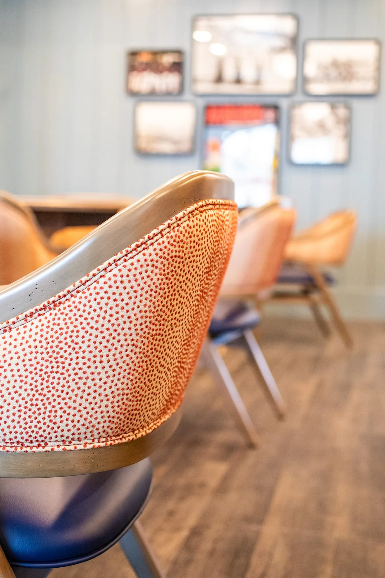 Senior living interior detail: coral dot chair with a navy seat, framed vintage photos on pale blue shiplap beyond