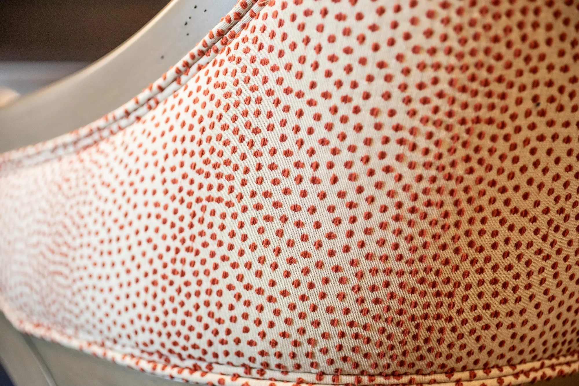 Senior living interior detail: cream fabric with dense coral dots on a curved chair back