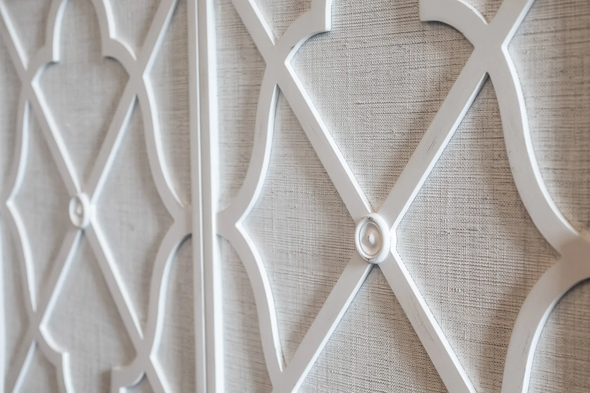 Senior living interior detail: white fretwork over grasscloth on two cabinet doors, at an angle