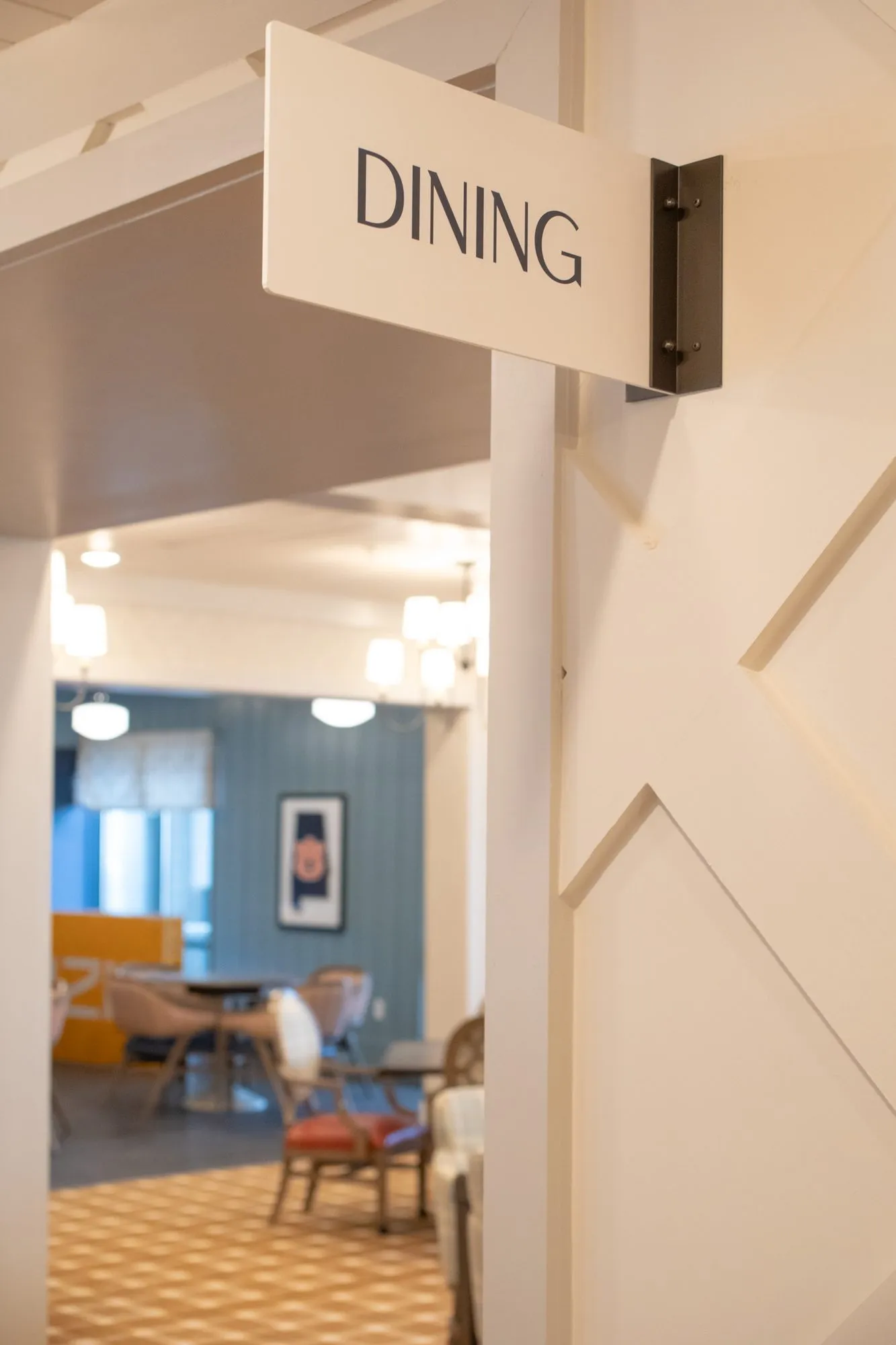 Senior living dining room entrance under a Dining sign, chairs and blue shiplap beyond