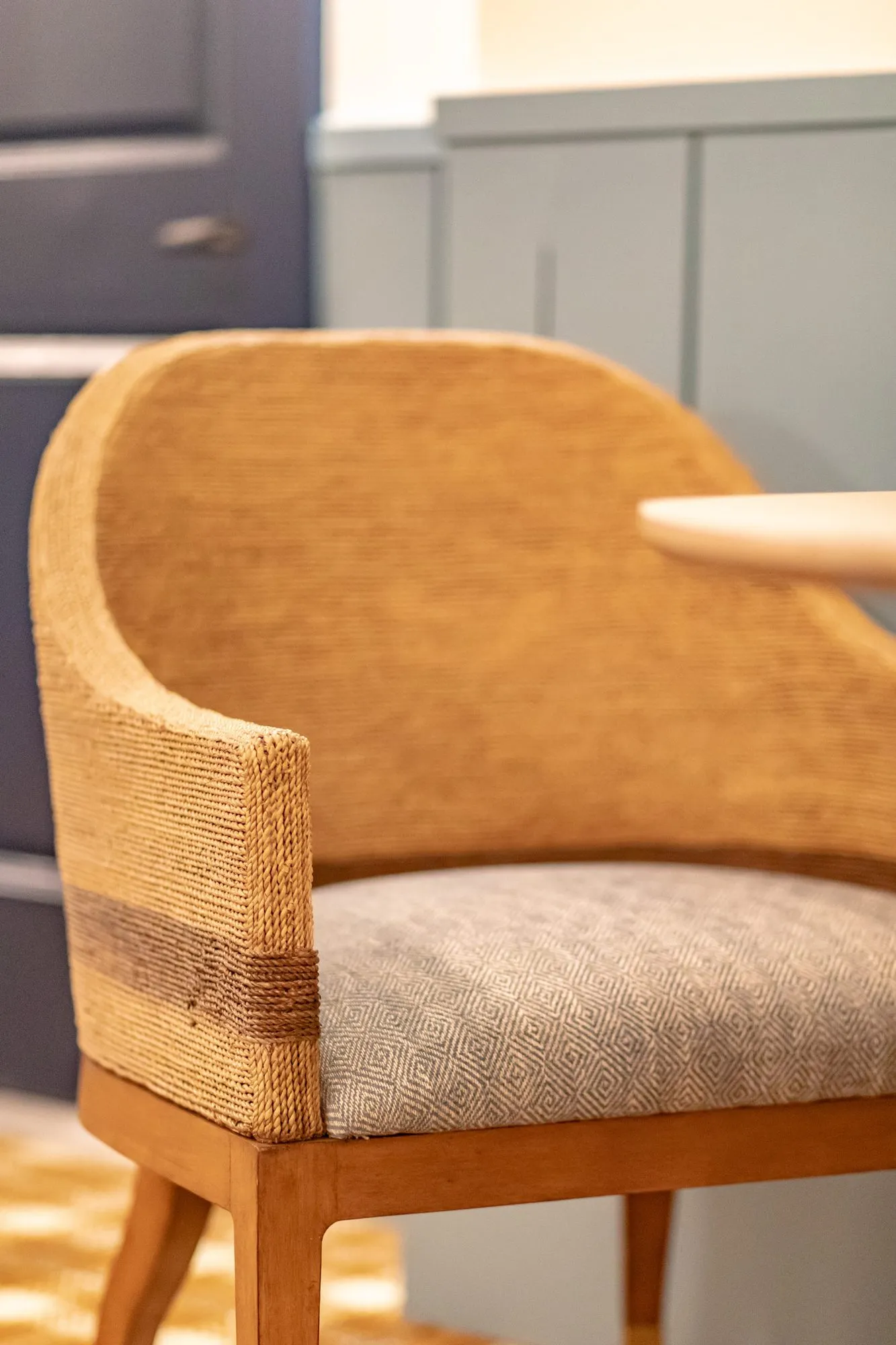 Senior living interior detail: woven rope back chair with a grey seat