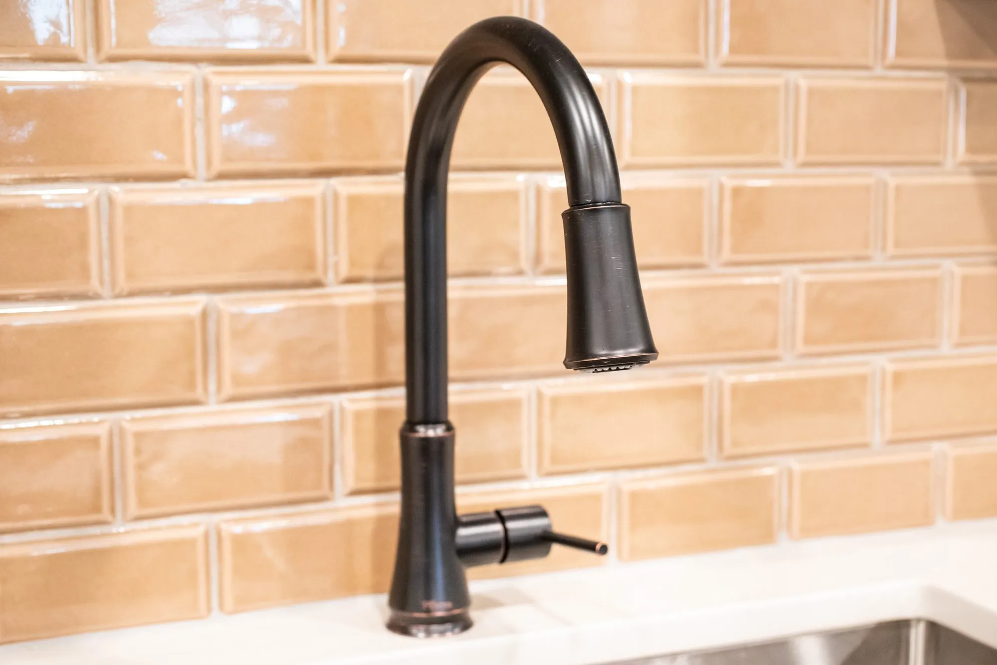 Senior living interior detail: oil rubbed bronze faucet against glossy tan subway tile