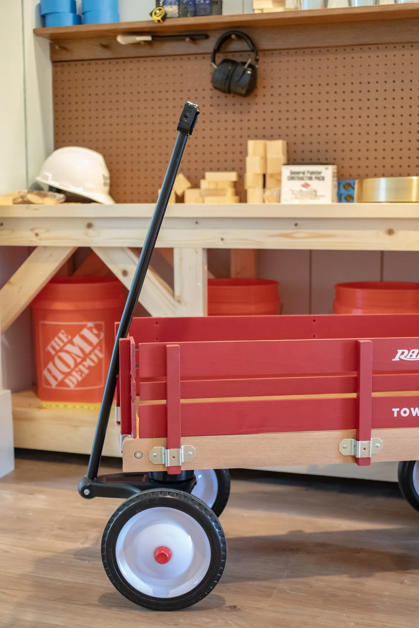 Senior living workshop with a red wooden wagon before a workbench with orange buckets, a hard hat and pegboard
