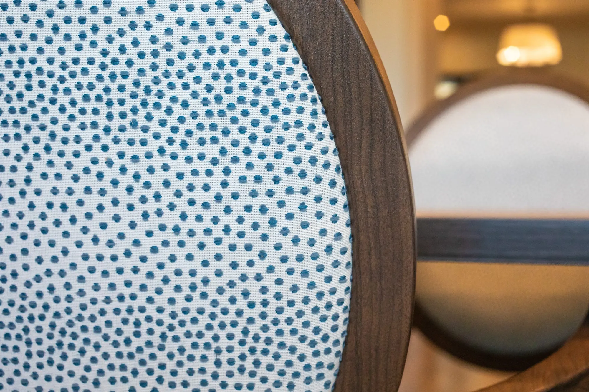 Senior living interior detail: blue dotted fabric chair back in a round wood frame