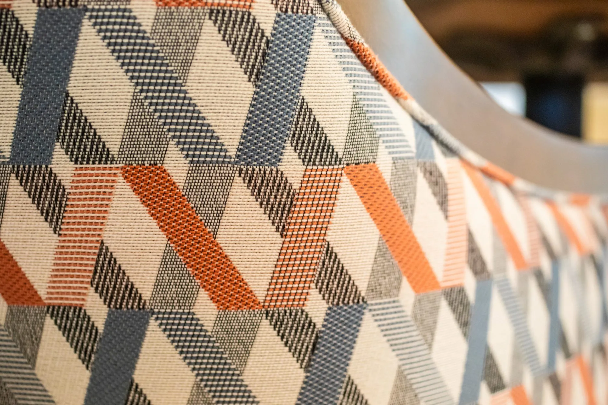 Senior living interior detail: geometric woven upholstery in navy, orange and cream on a curved chair