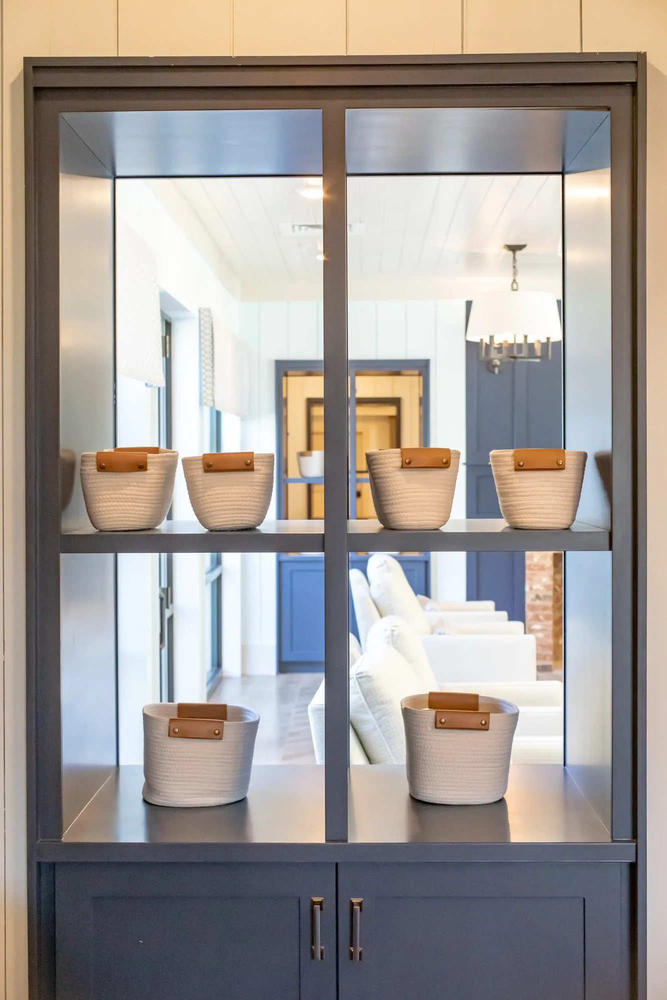 Senior living interior detail: navy display cabinet with open shelves of woven baskets, a corridor visible through it