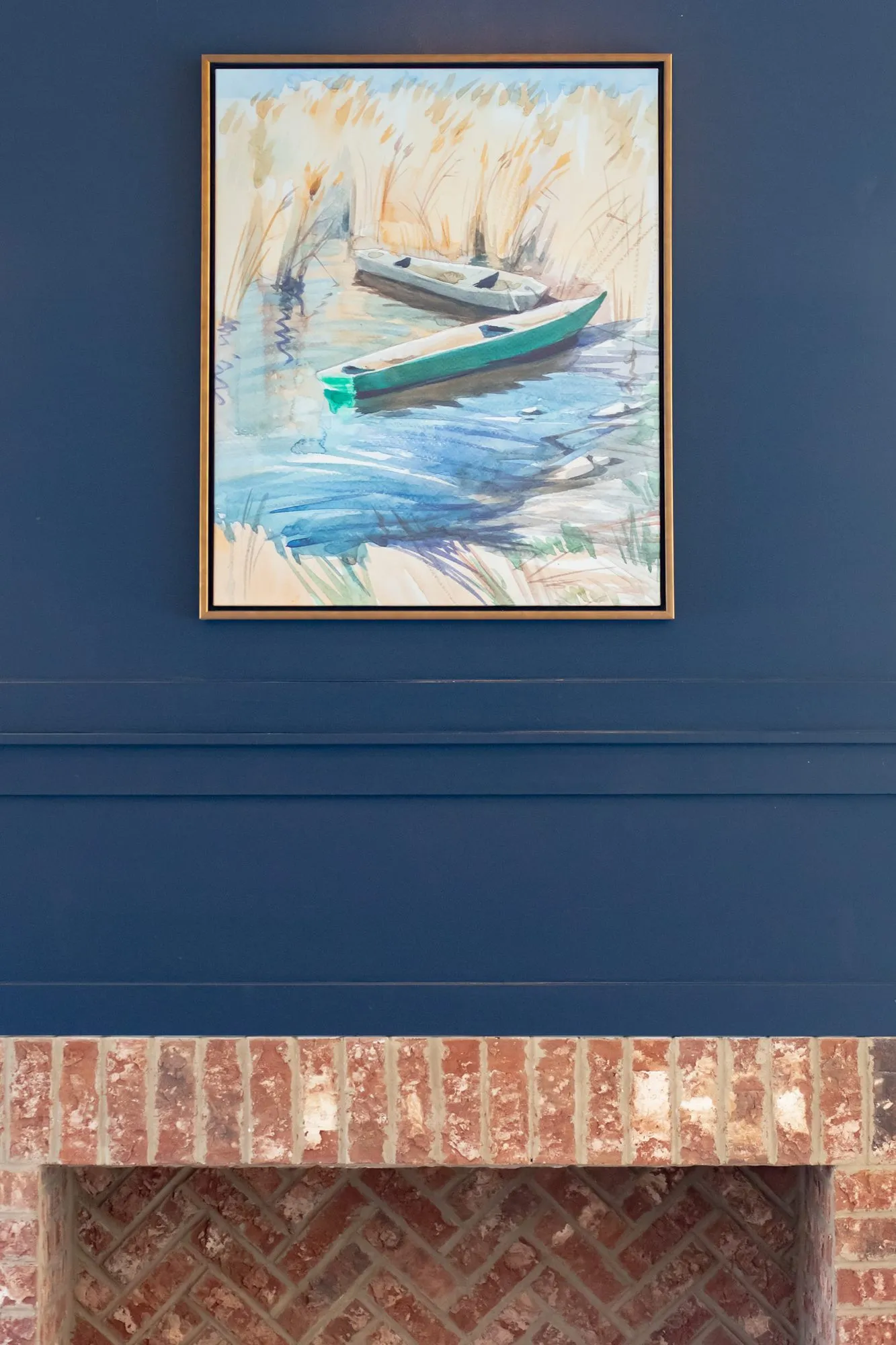 Senior living interior detail: boat painting on a navy wall above a herringbone brick firebox