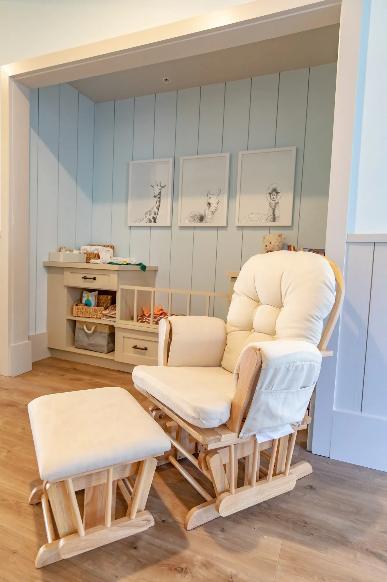 Senior living nursery nook with a glider and ottoman, a changing station and three animal sketches