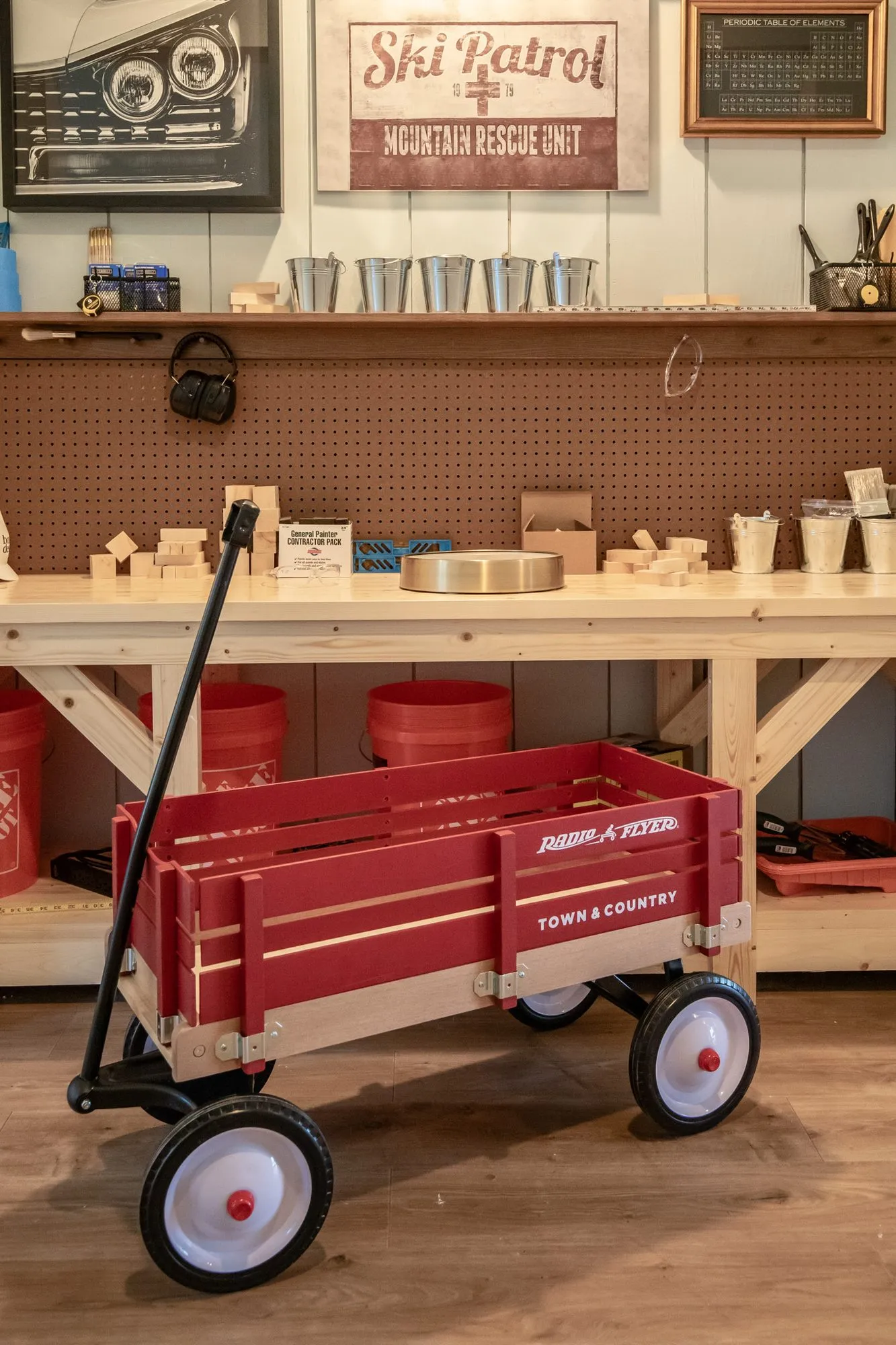 Senior living workshop with a red wagon before a workbench with buckets under a Ski Patrol sign