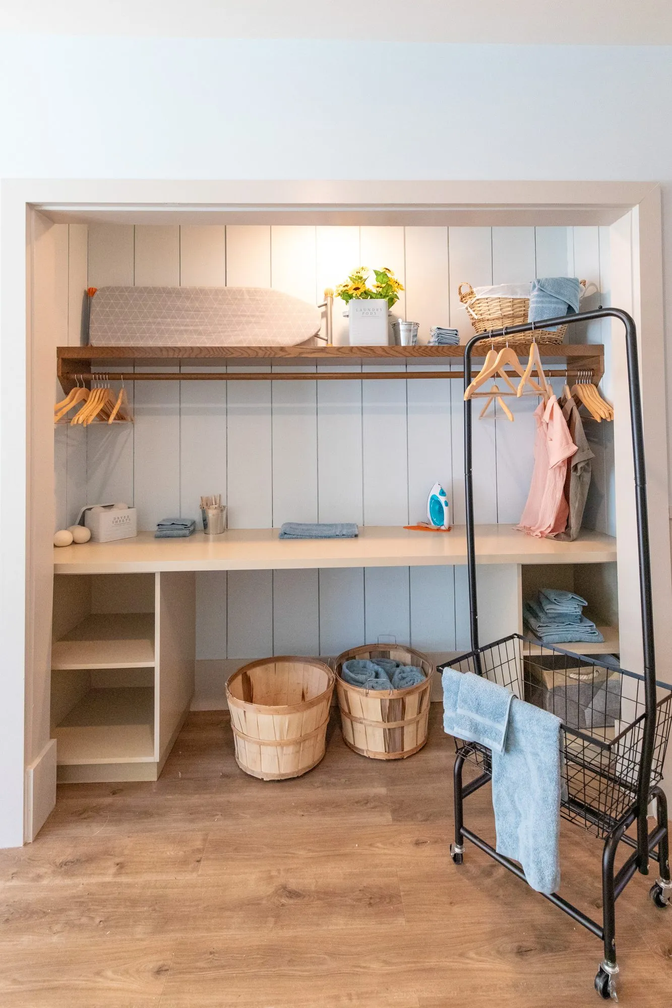 Senior living laundry nook with an ironing board, hanging rail, bushel baskets and a rolling cart