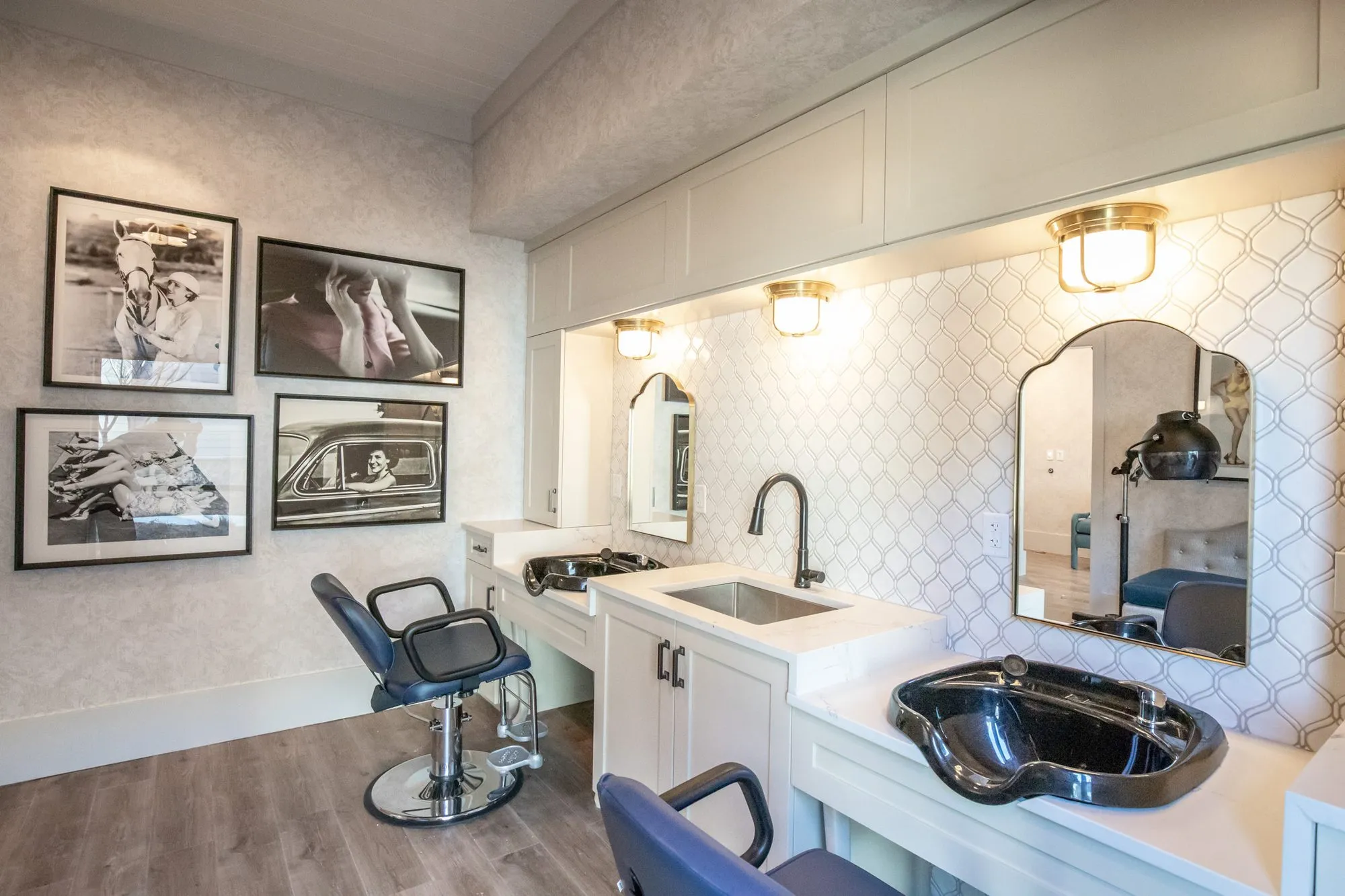Senior living salon from the side, styling chair, black and white photographs and shampoo bowls under arched mirrors