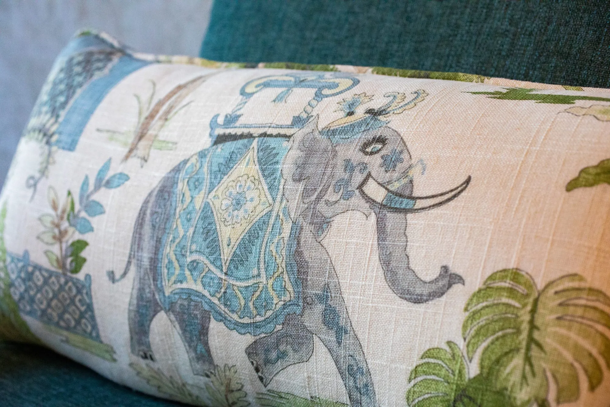 Senior living interior detail: lumbar pillow printed with an elephant and palm leaves on a teal chair