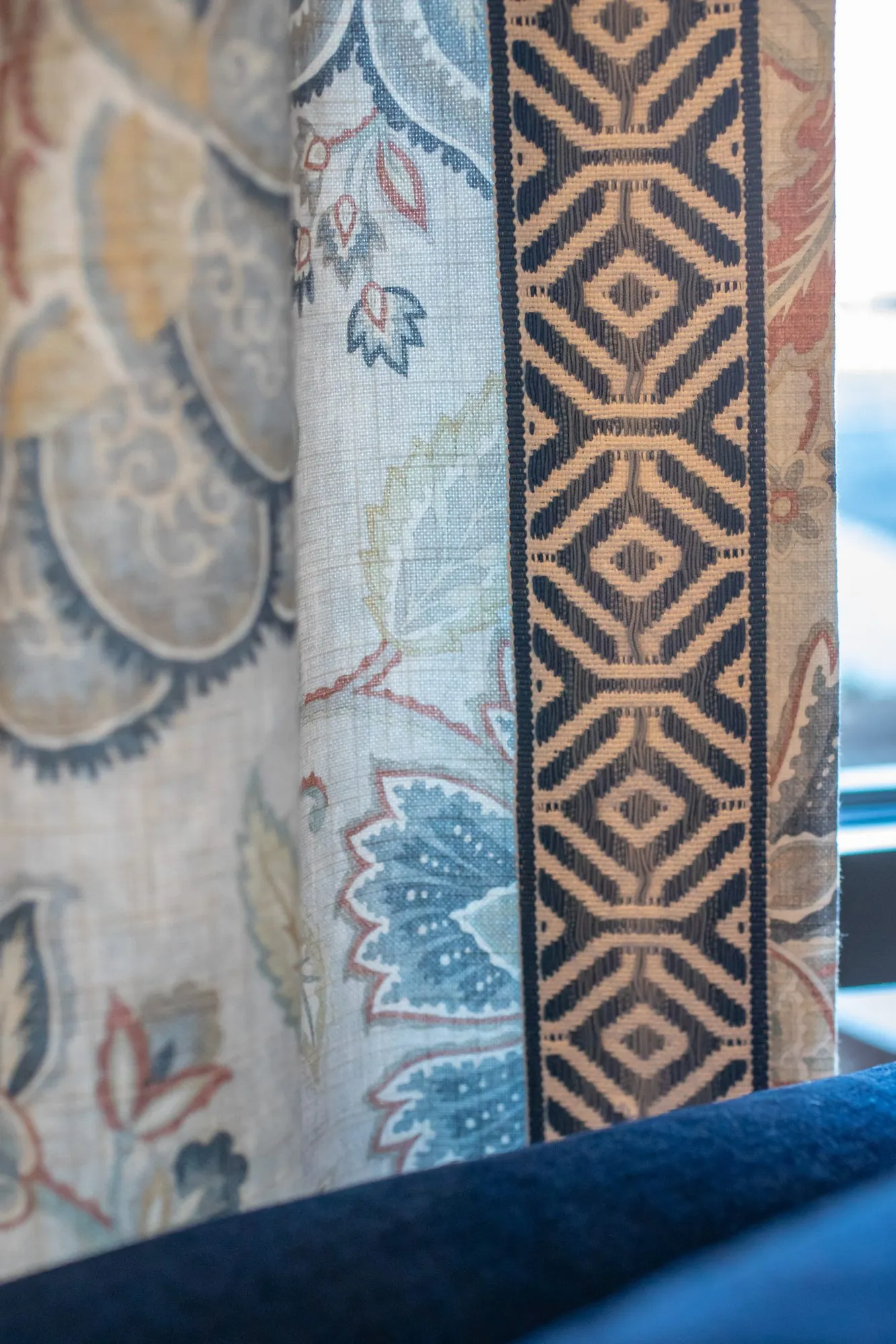 Senior living interior detail: floral drapery with a navy and tan geometric border above a navy sofa