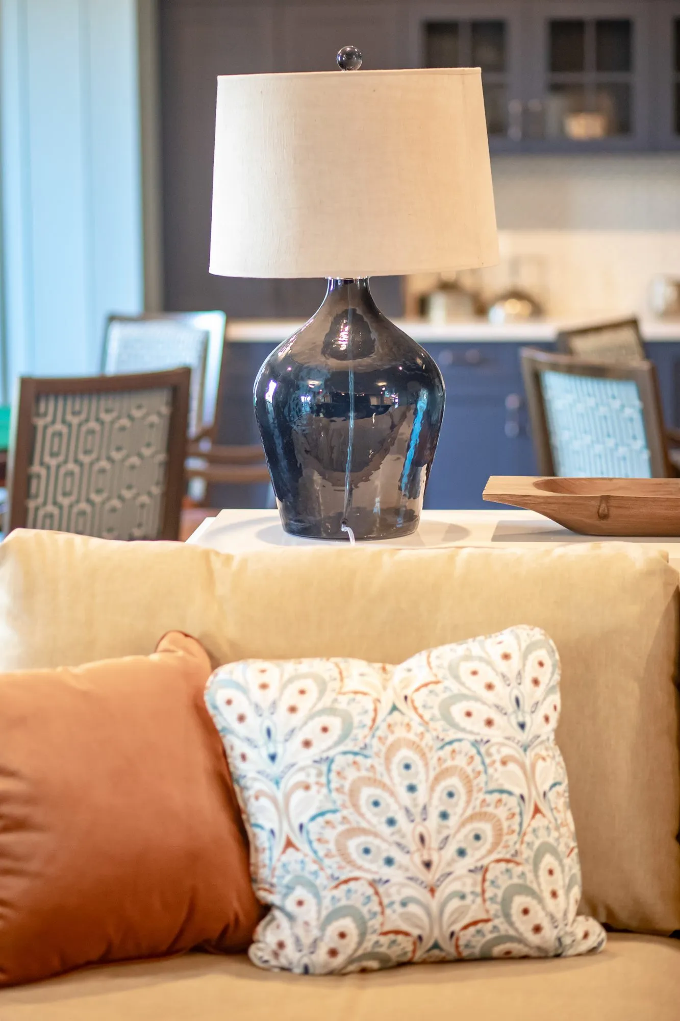 Senior living interior detail: navy glass lamp behind a camel sofa with paisley and orange pillows