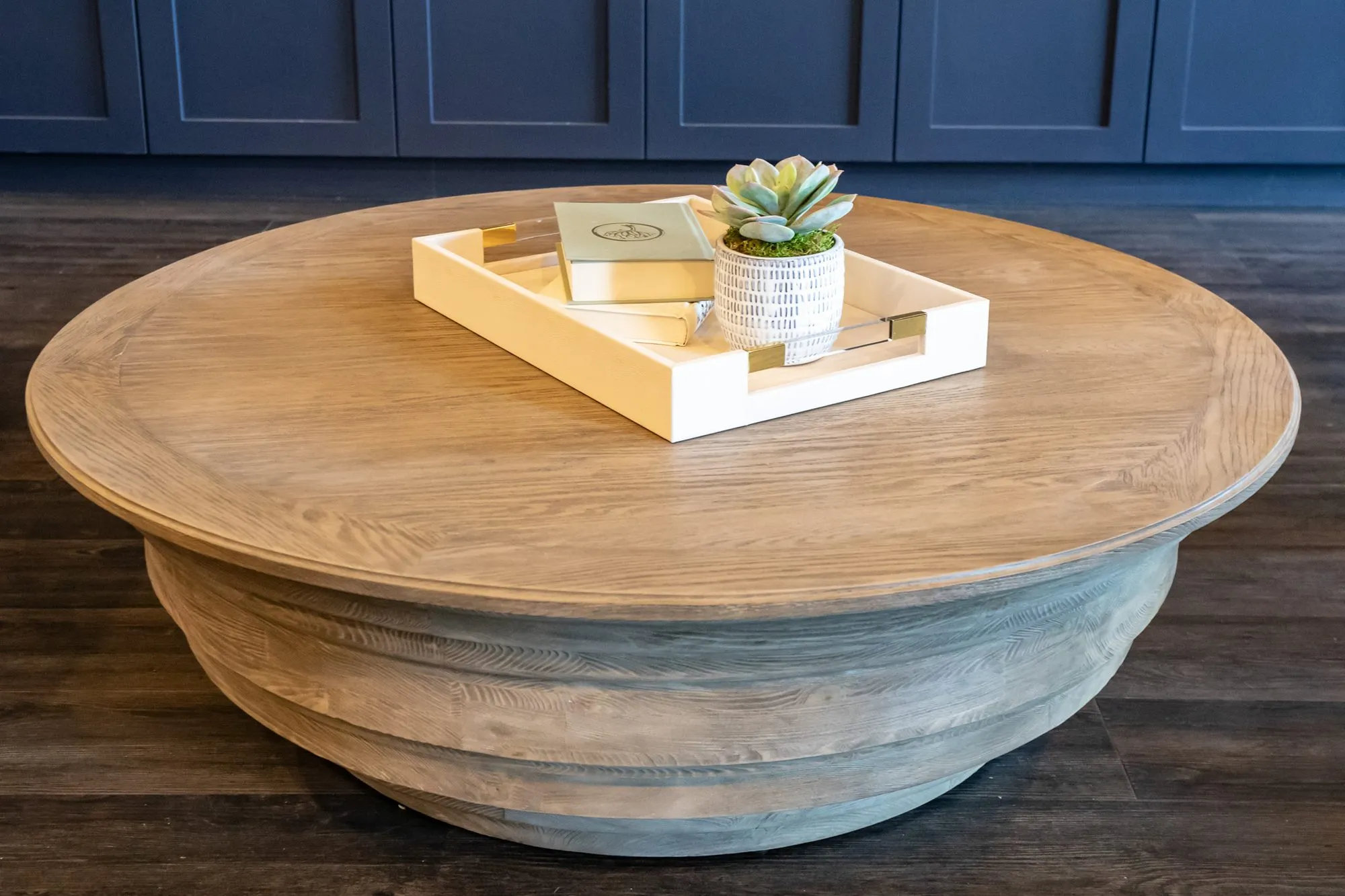Senior living interior detail: round wood coffee table with a white tray holding a book and a succulent