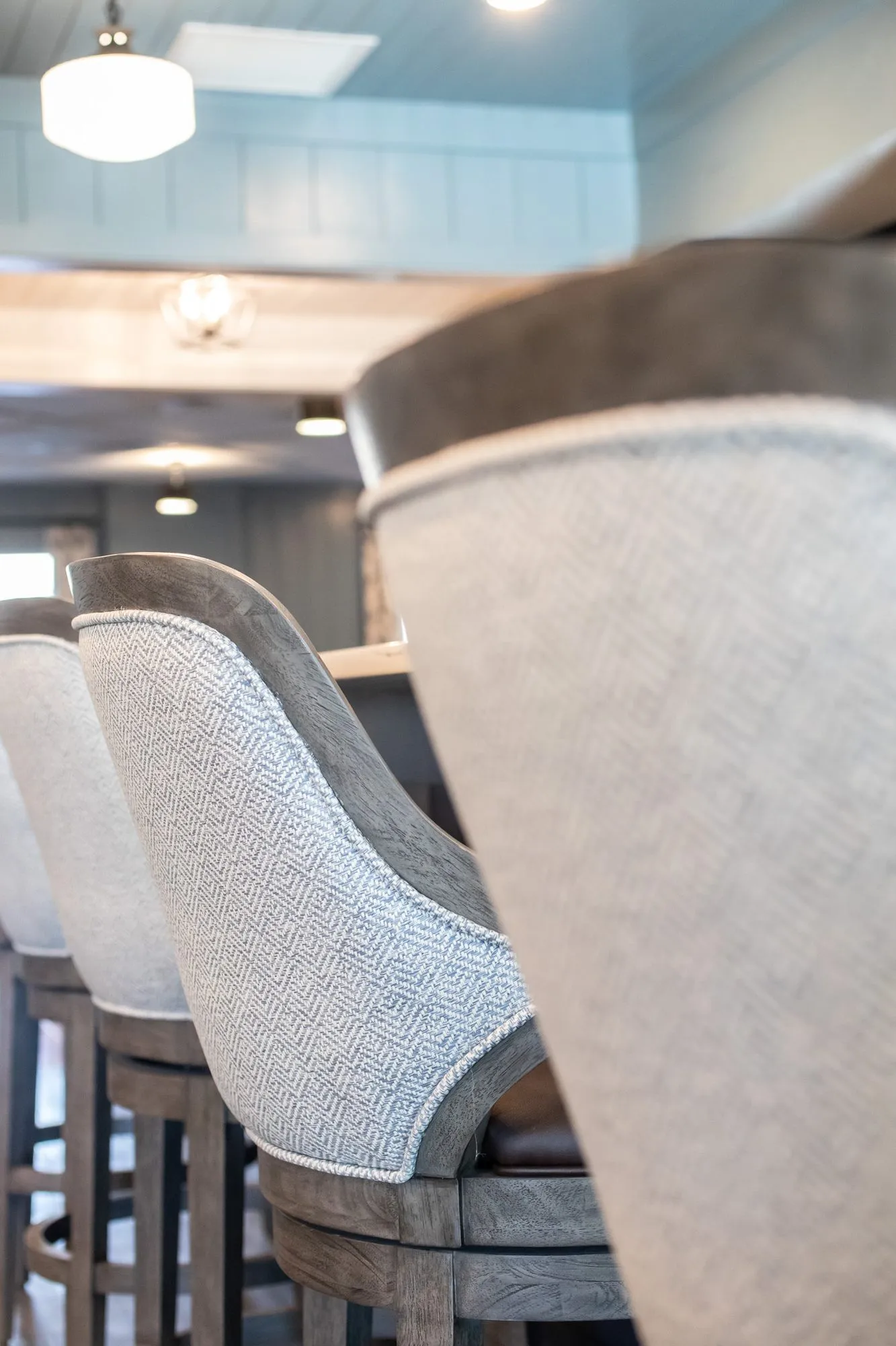Senior living interior detail: herringbone upholstered barstools with wood frames at a counter