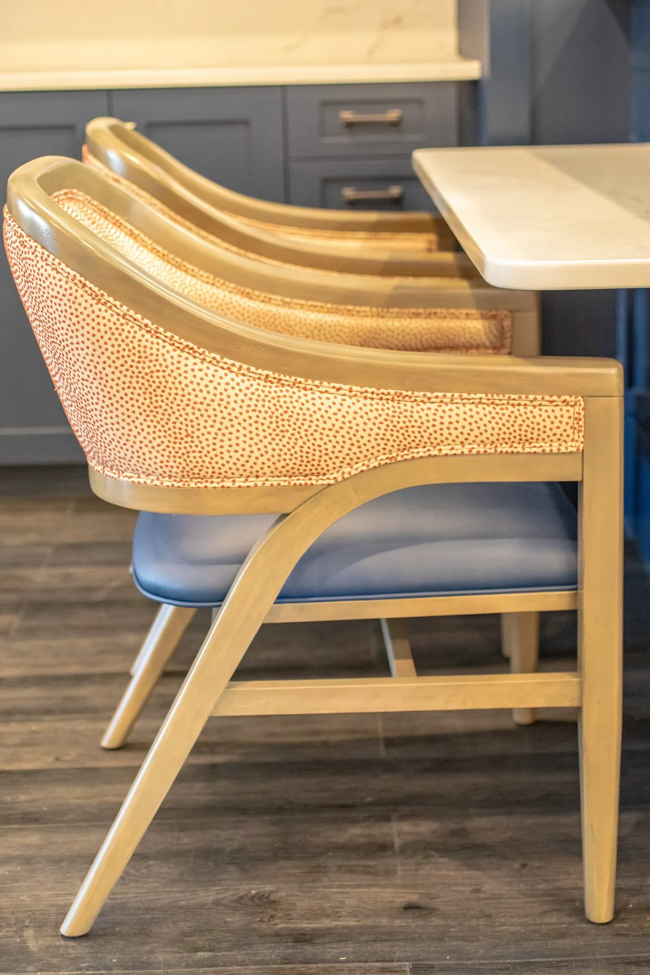 Senior living interior detail: coral dot armchairs with blue seats tucked under a white counter