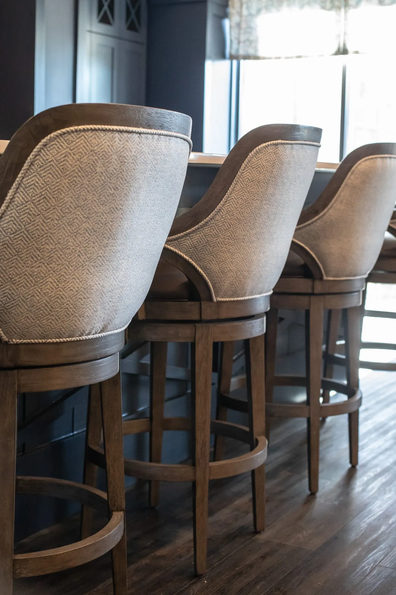 Senior living bar lined with herringbone upholstered barstools with wood frames