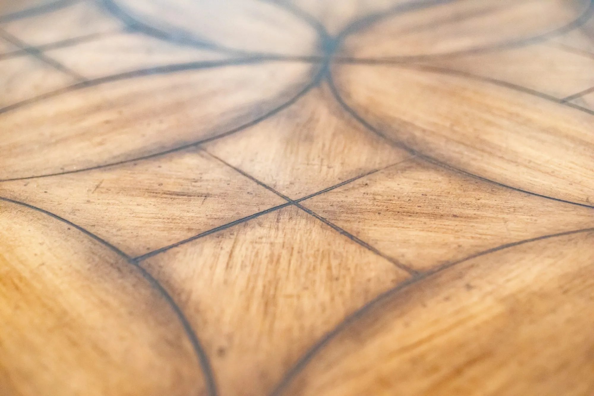 Senior living interior detail: wood table top with a curved inlaid quatrefoil pattern