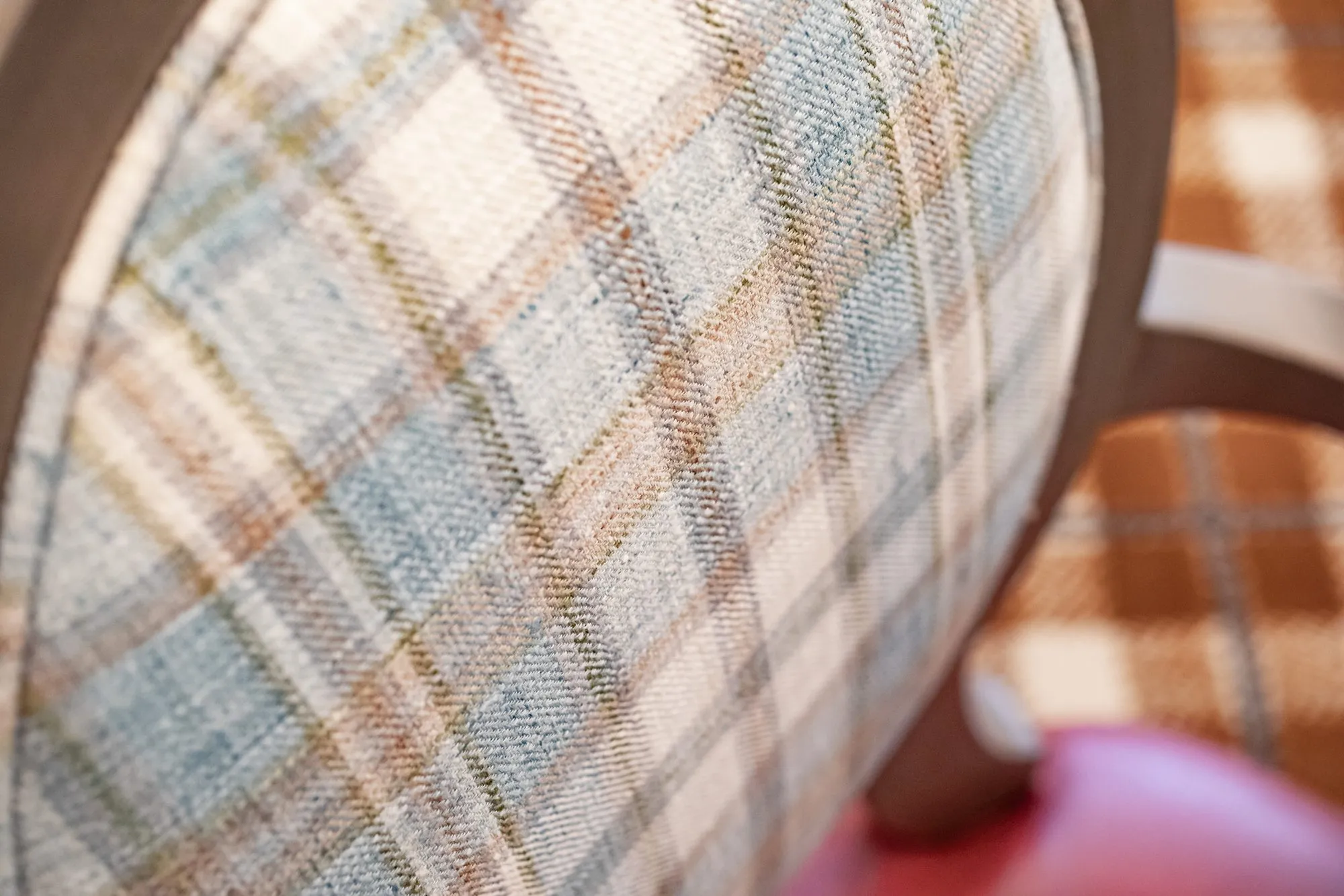 Senior living interior detail: blue and tan plaid chair back with a coral seat edge
