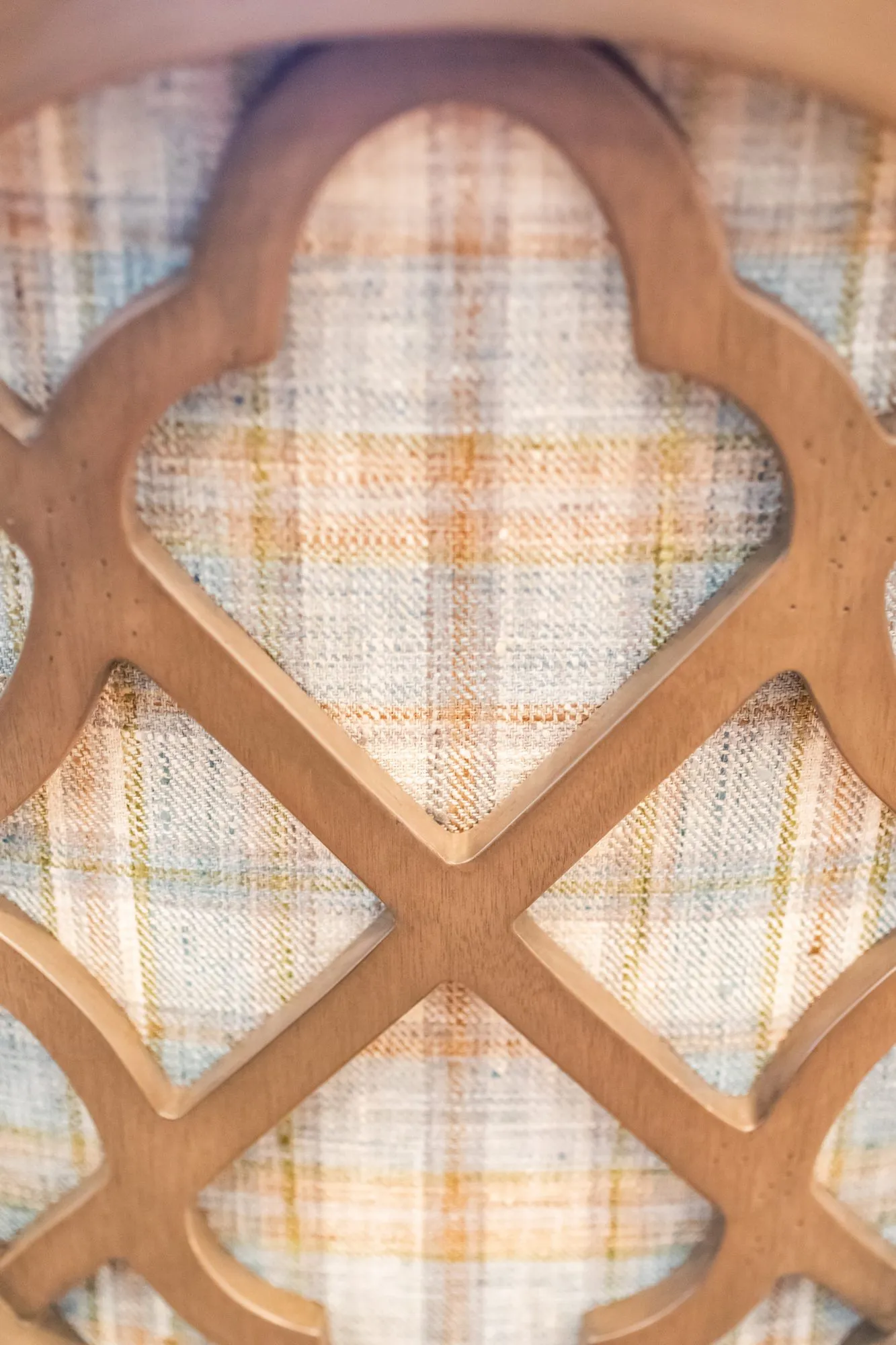 Senior living interior detail: quatrefoil lattice chair back over plaid fabric