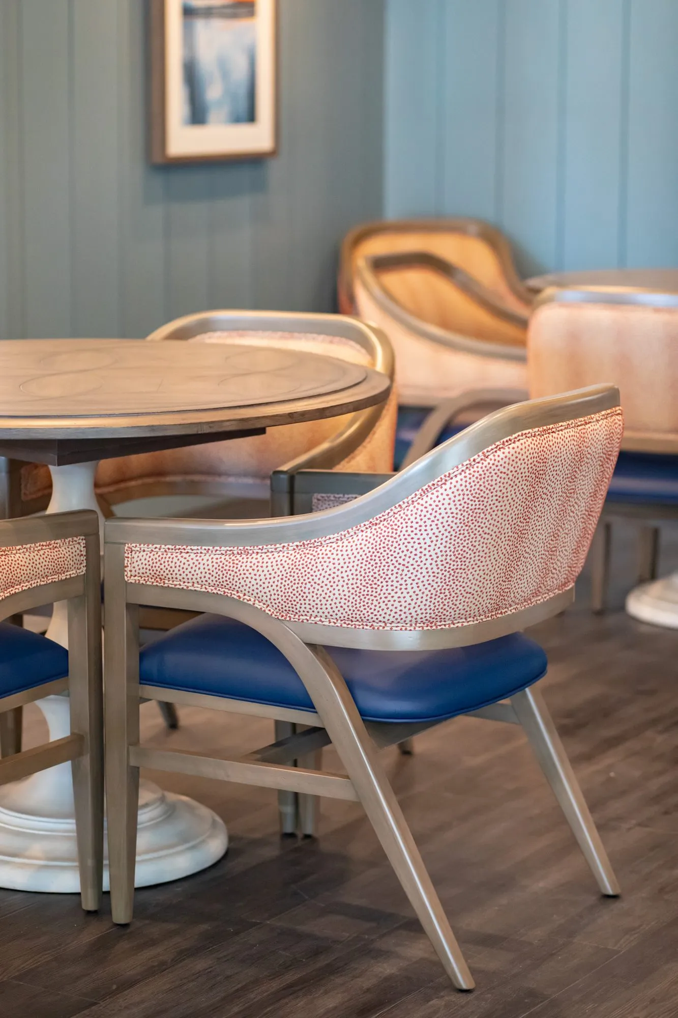 Senior living interior detail: coral dot chairs with blue seats at a round pedestal table