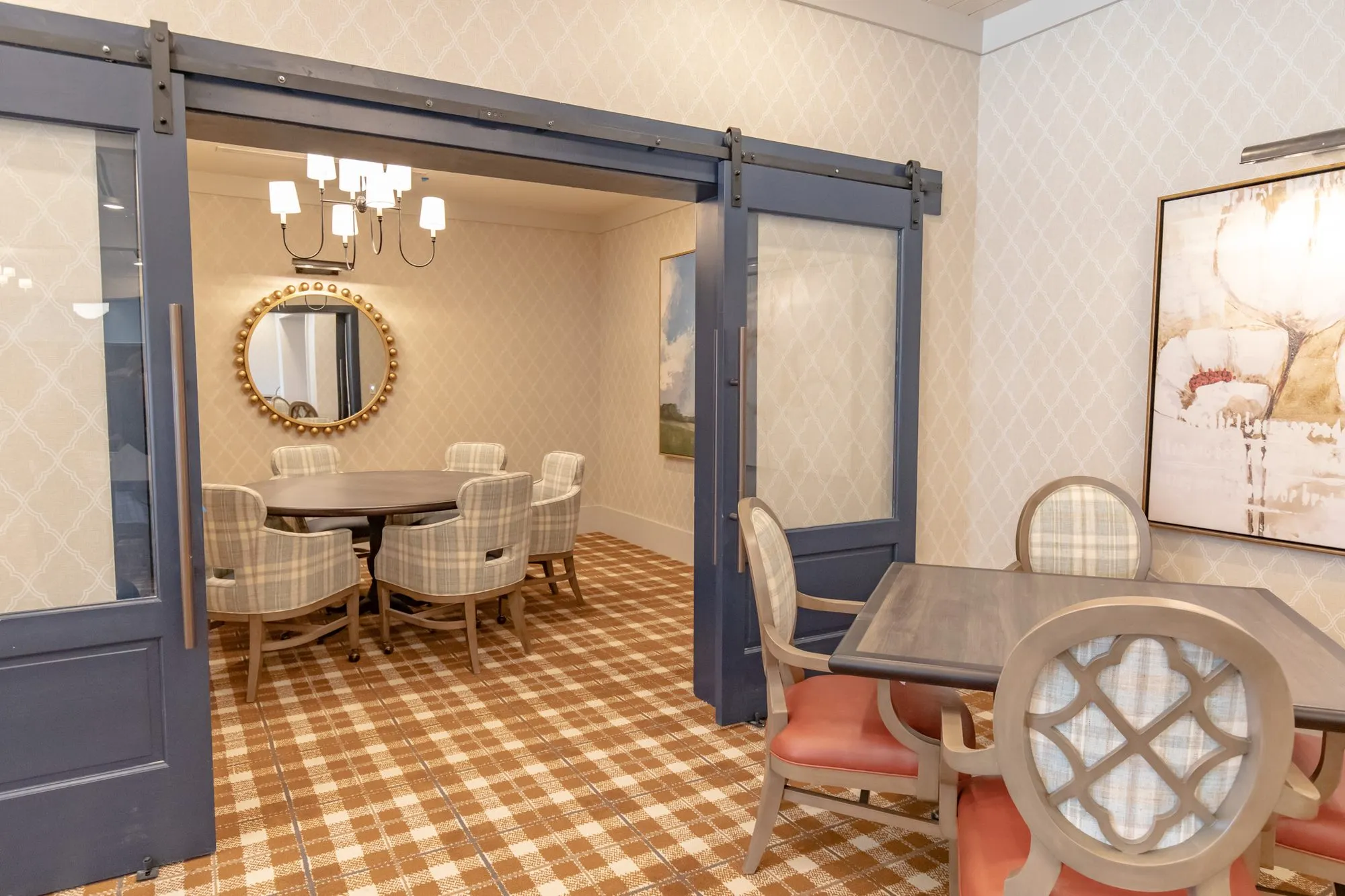 Senior living private dining room through open navy barn doors, a quatrefoil chair at a table in front