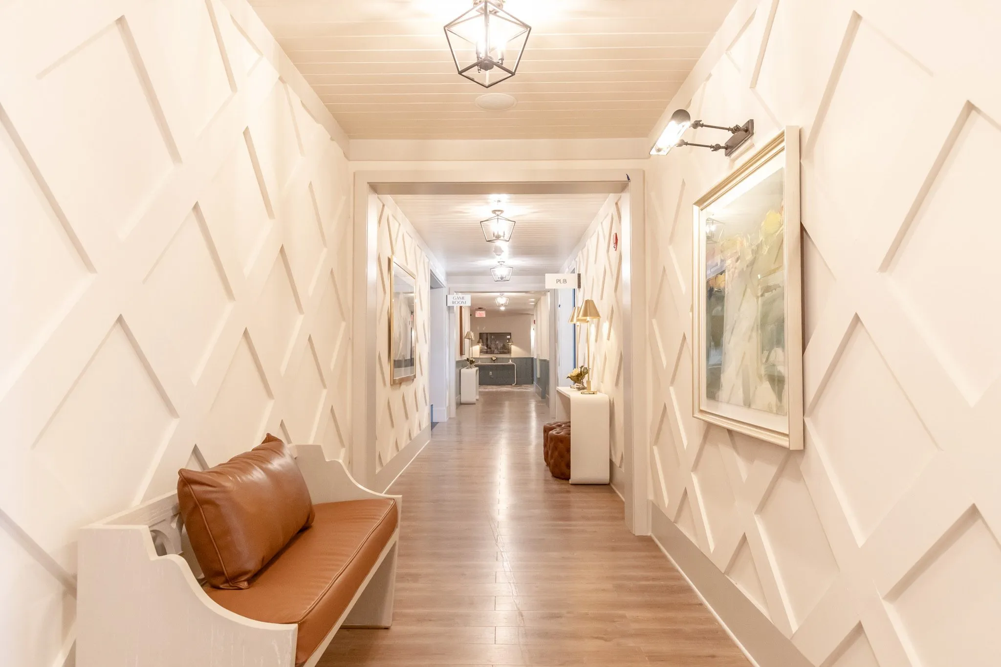 Senior living corridor with diamond lattice millwork above a leather bench under a lantern pendant