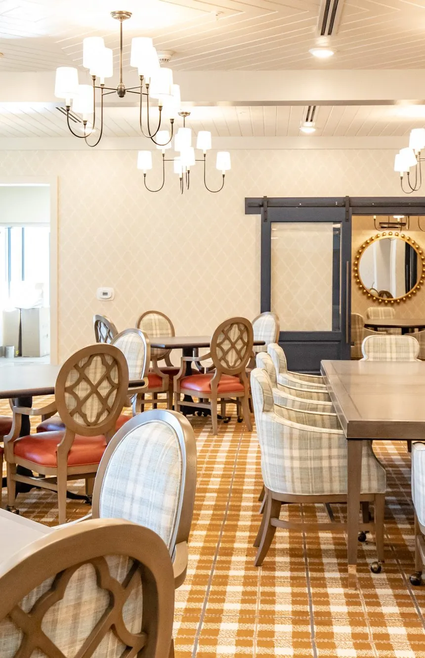 Senior living dining room with trellis wallpaper and plaid armchairs, interior design by Banko Design at The Phoenix at Opelika, Opelika, Alabama