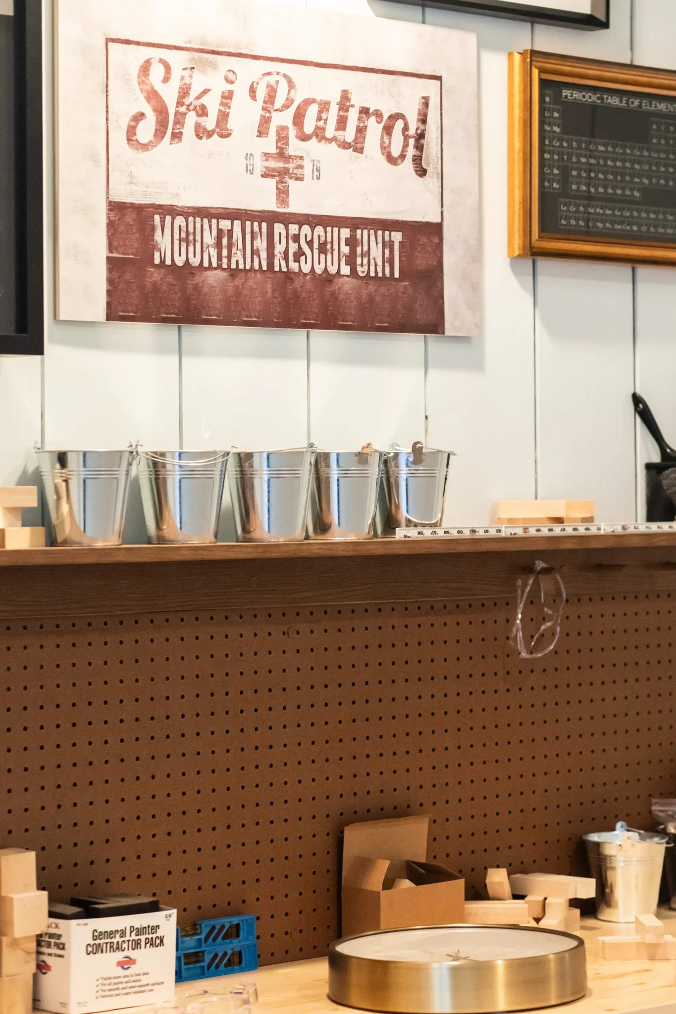 Senior living memory care workshop with a Ski Patrol sign above a pegboard bench lined with galvanised buckets