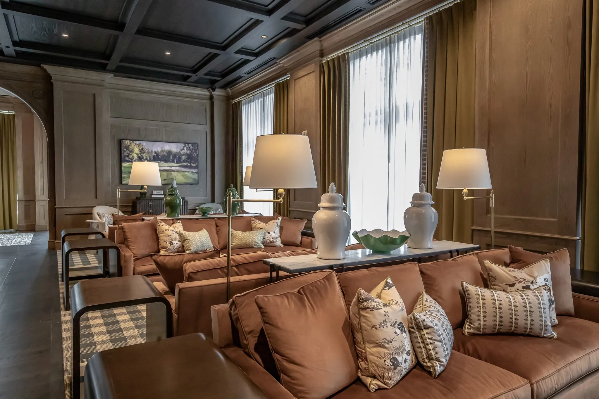 Private club lounge with brown leather sofas along the window wall and ginger jars on a console