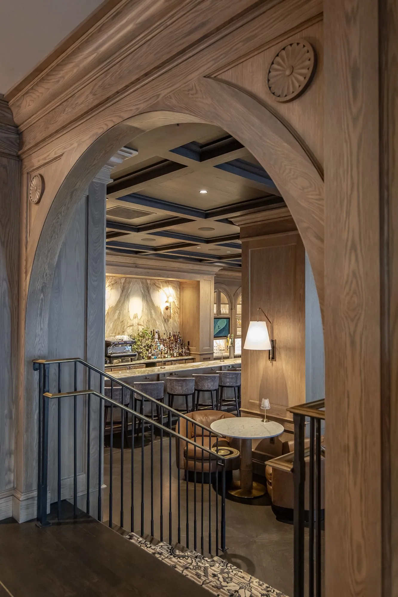 Private club stair with an oak archway at the top looking down into the bar lounge and its coffered ceiling