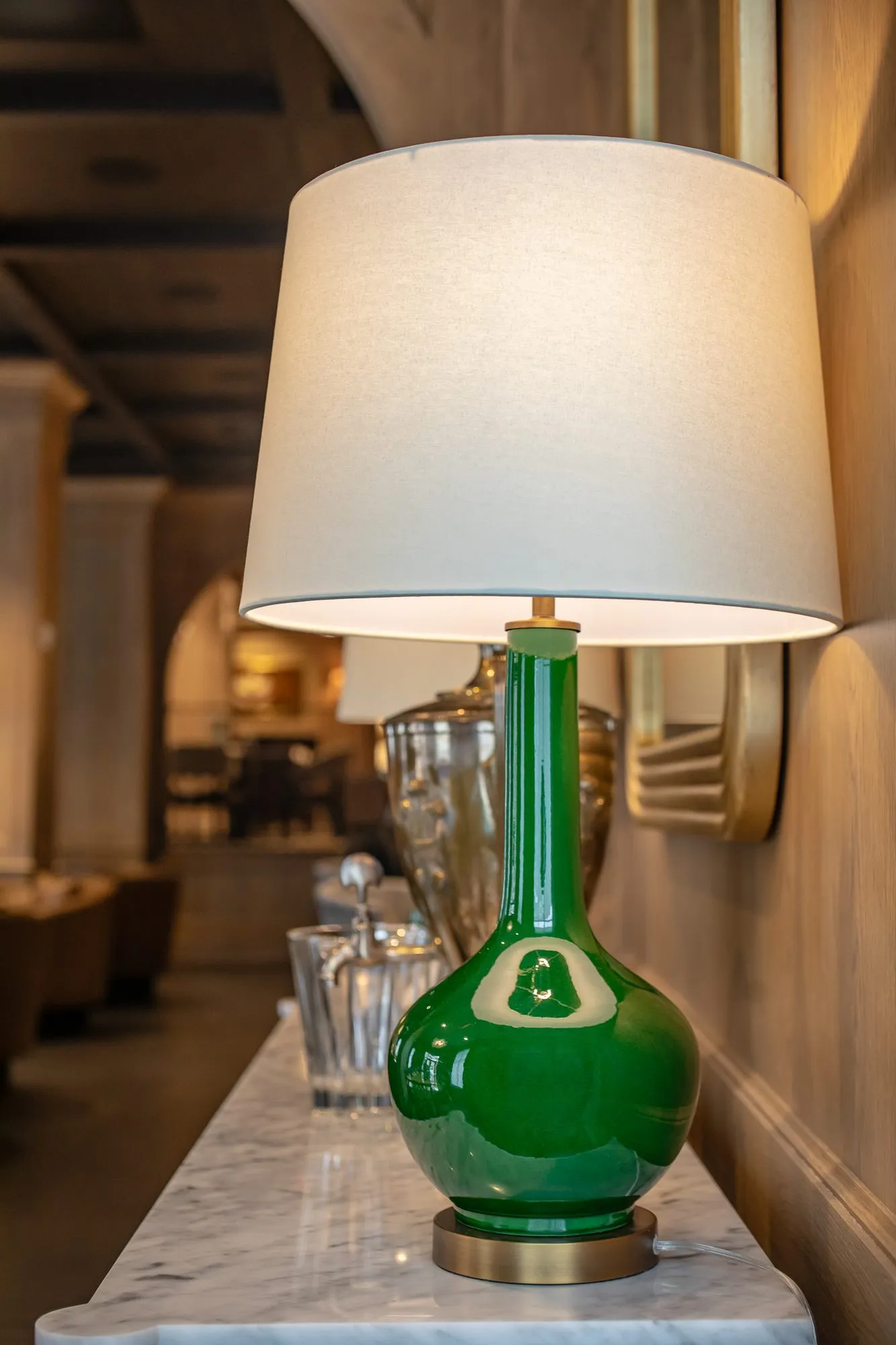 Private club interior detail: green glass lamp with a white shade on a marble ledge