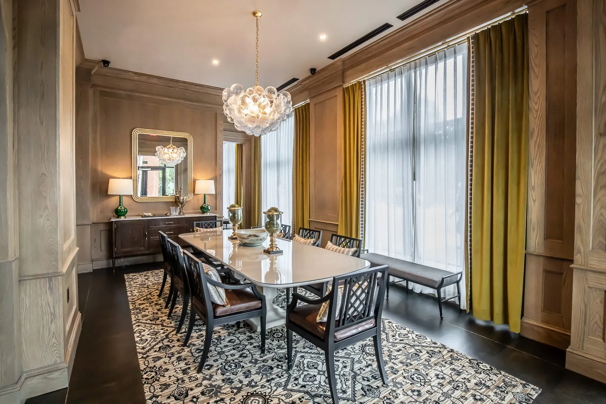 Private club private dining room with a bubble glass chandelier over the marble table and mustard velvet drapes