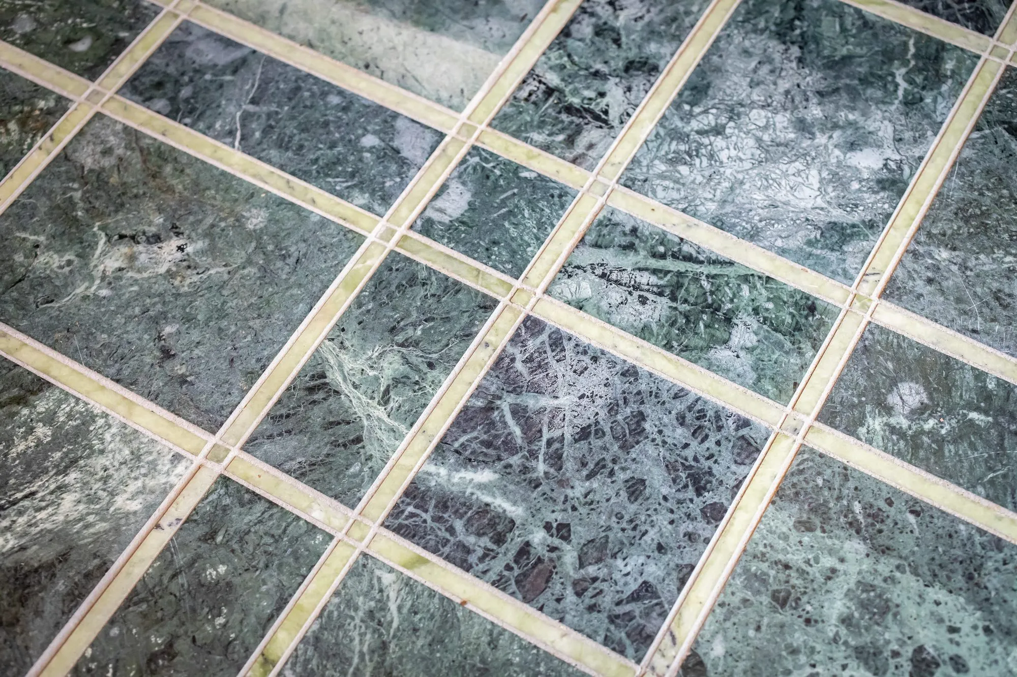 Private club interior detail: green marble floor tiles set in a grid of pale stone strips