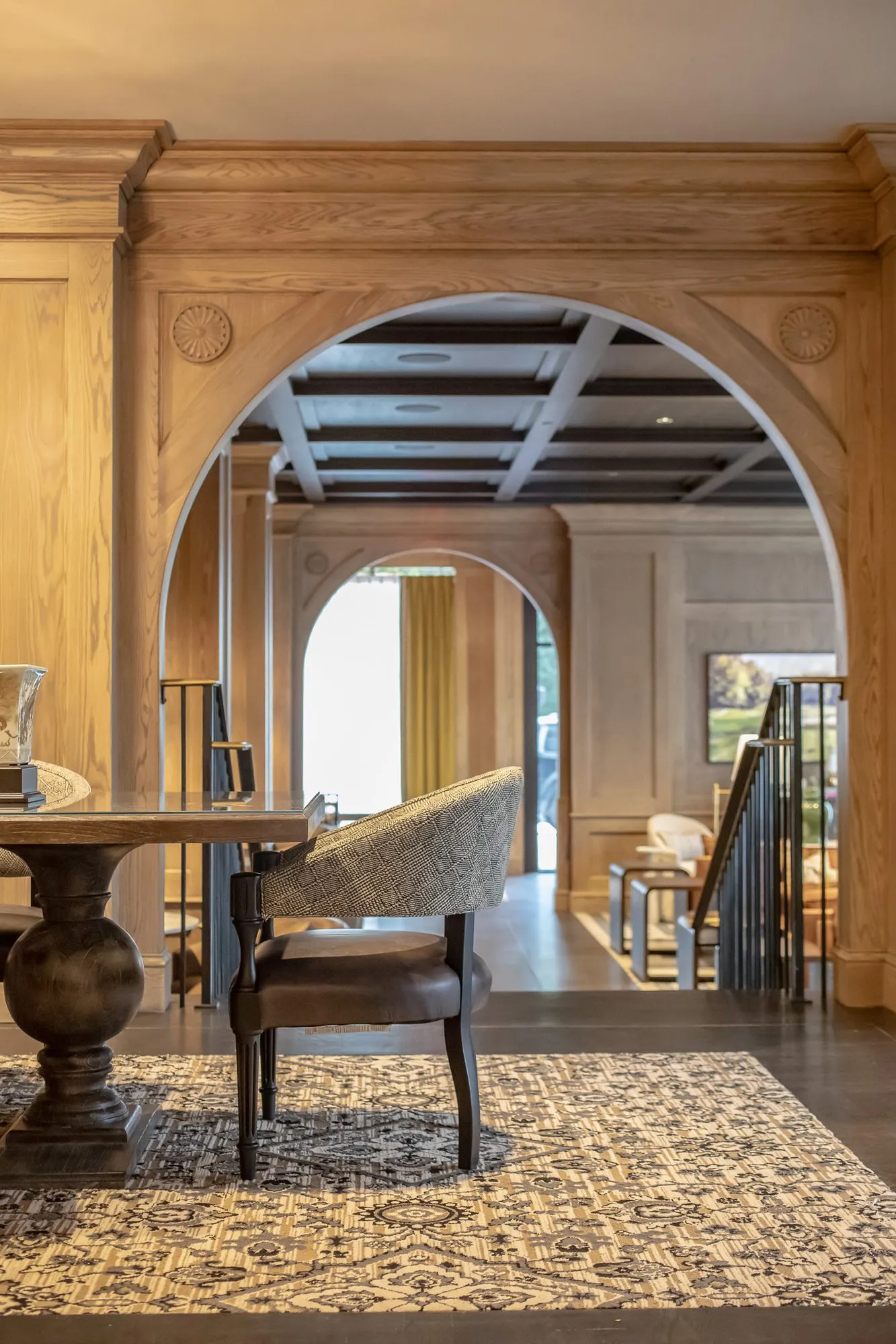 Private club interior detail: oak archway with carved rosettes framing a further arch, a dining table and chair in front