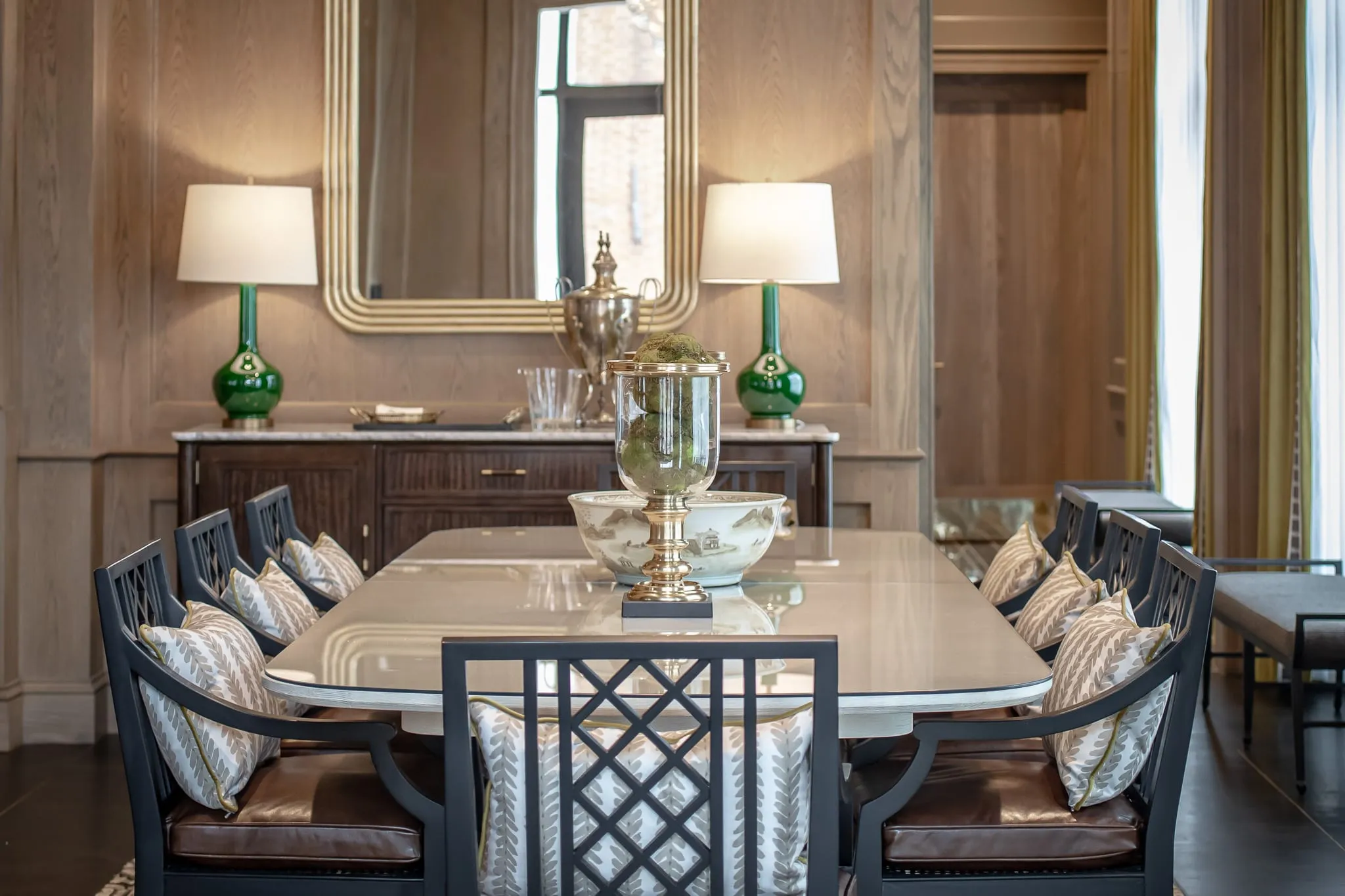 Private club private dining room with a white marble table and black fretwork chairs beneath a gilt mirror
