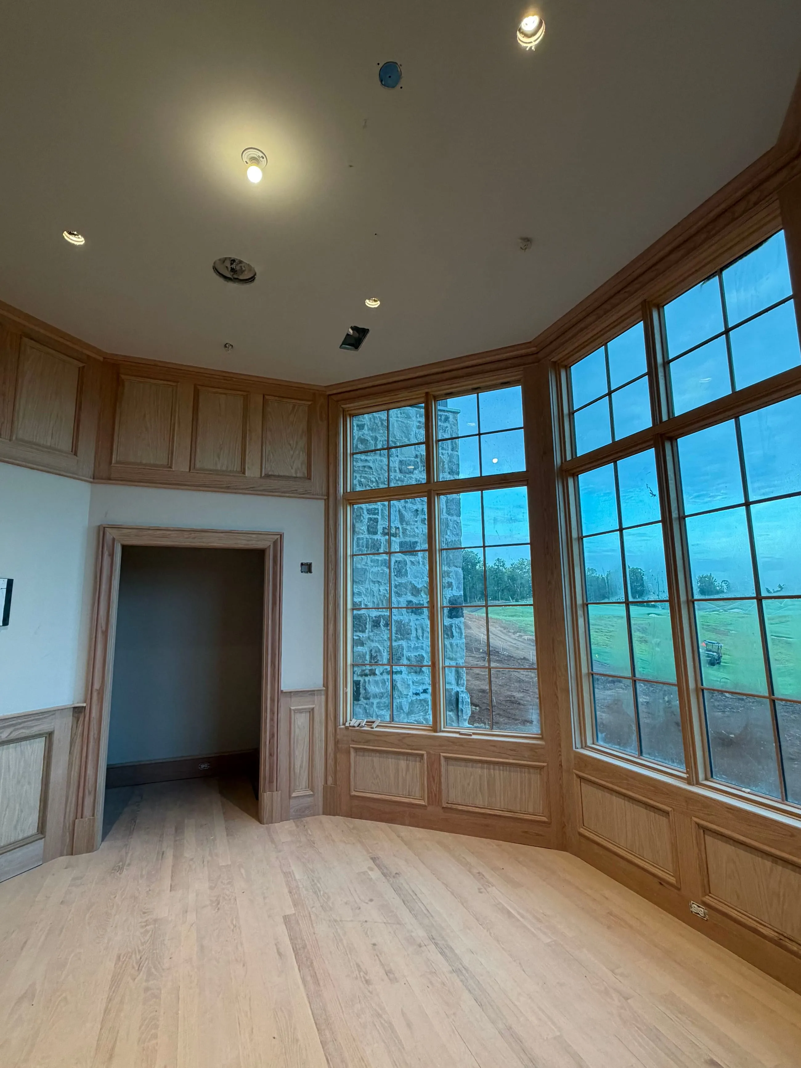 Private club clubhouse under construction: founders sitting room with a panelled bay window wall open to the course