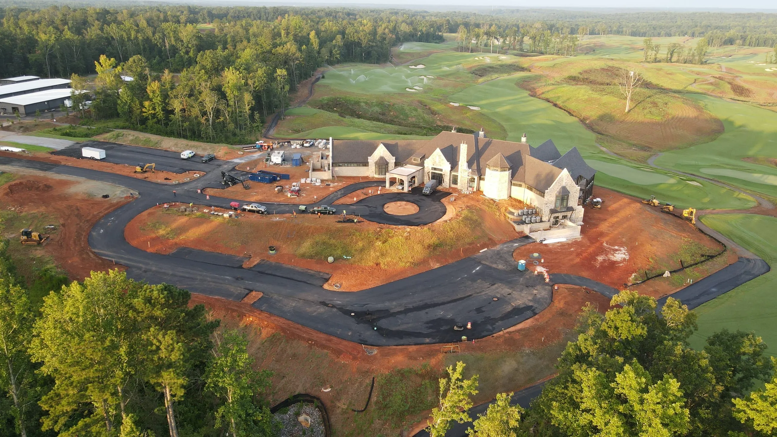Private club clubhouse under construction: wide aerial of the building and the surrounding course