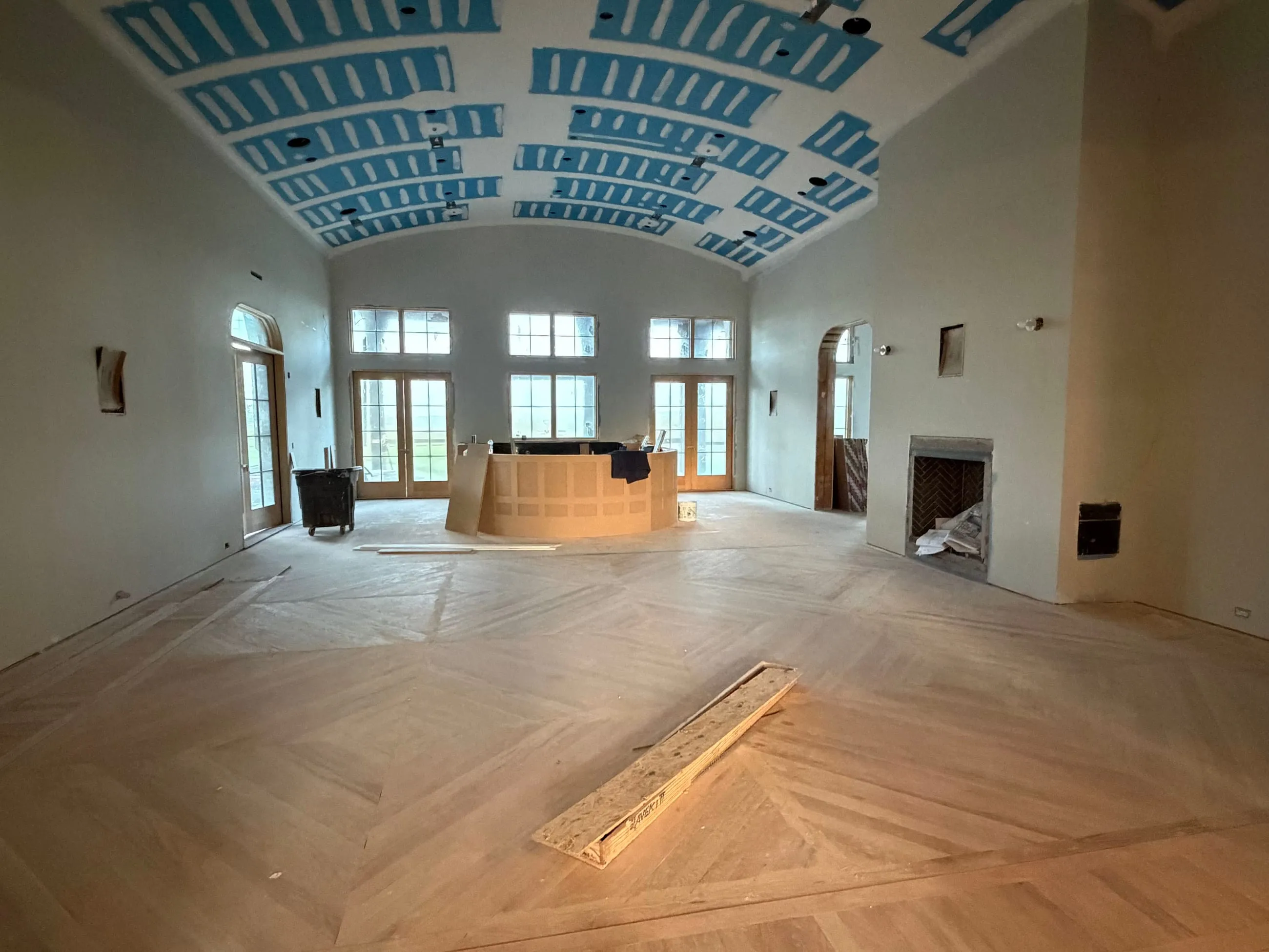 Private club clubhouse under construction: barrel-vaulted room with herringbone wood flooring, a curved counter, a fireplace