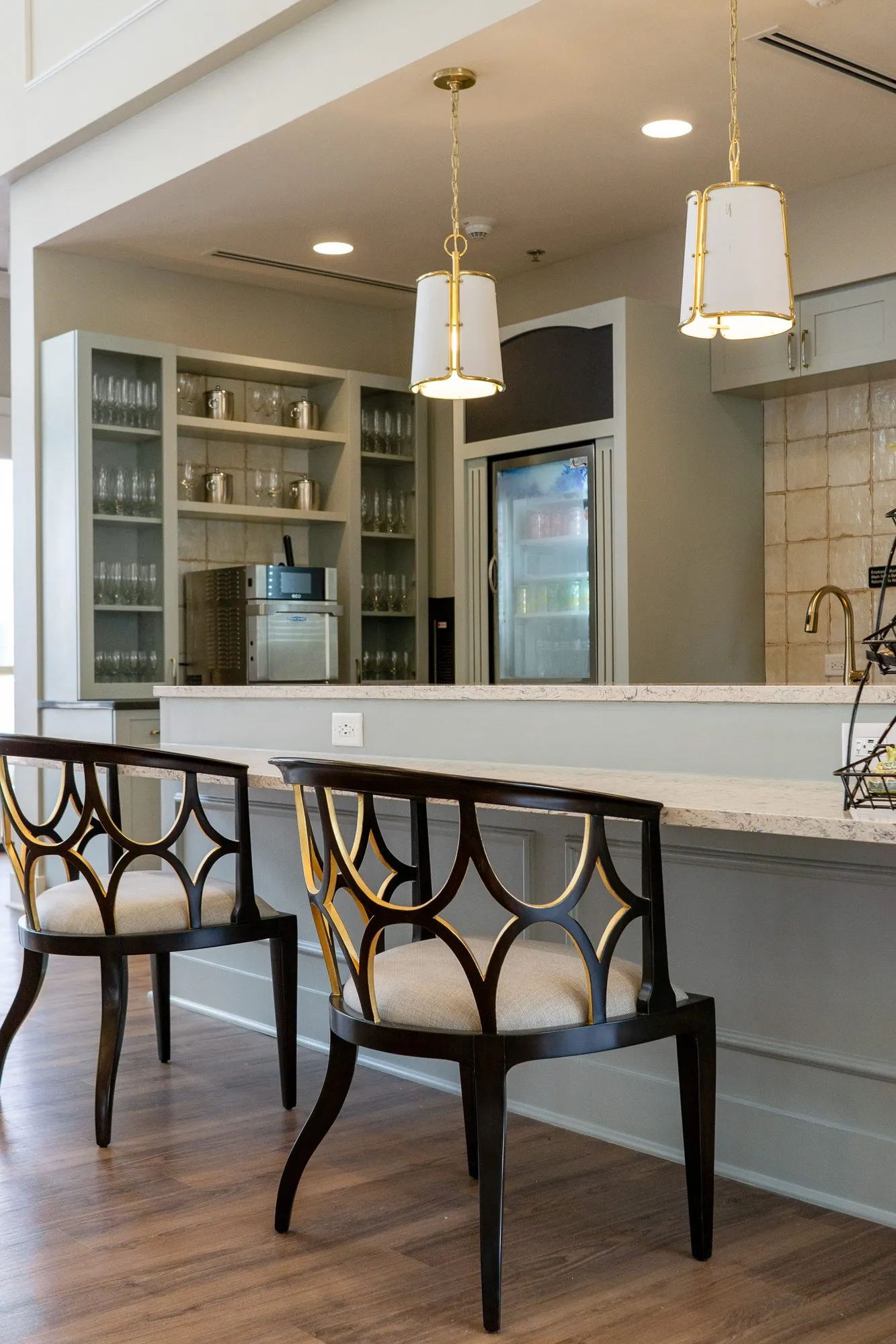 Senior living kitchen with fretwork back counter chairs at the stone counter, open glass shelving at left
